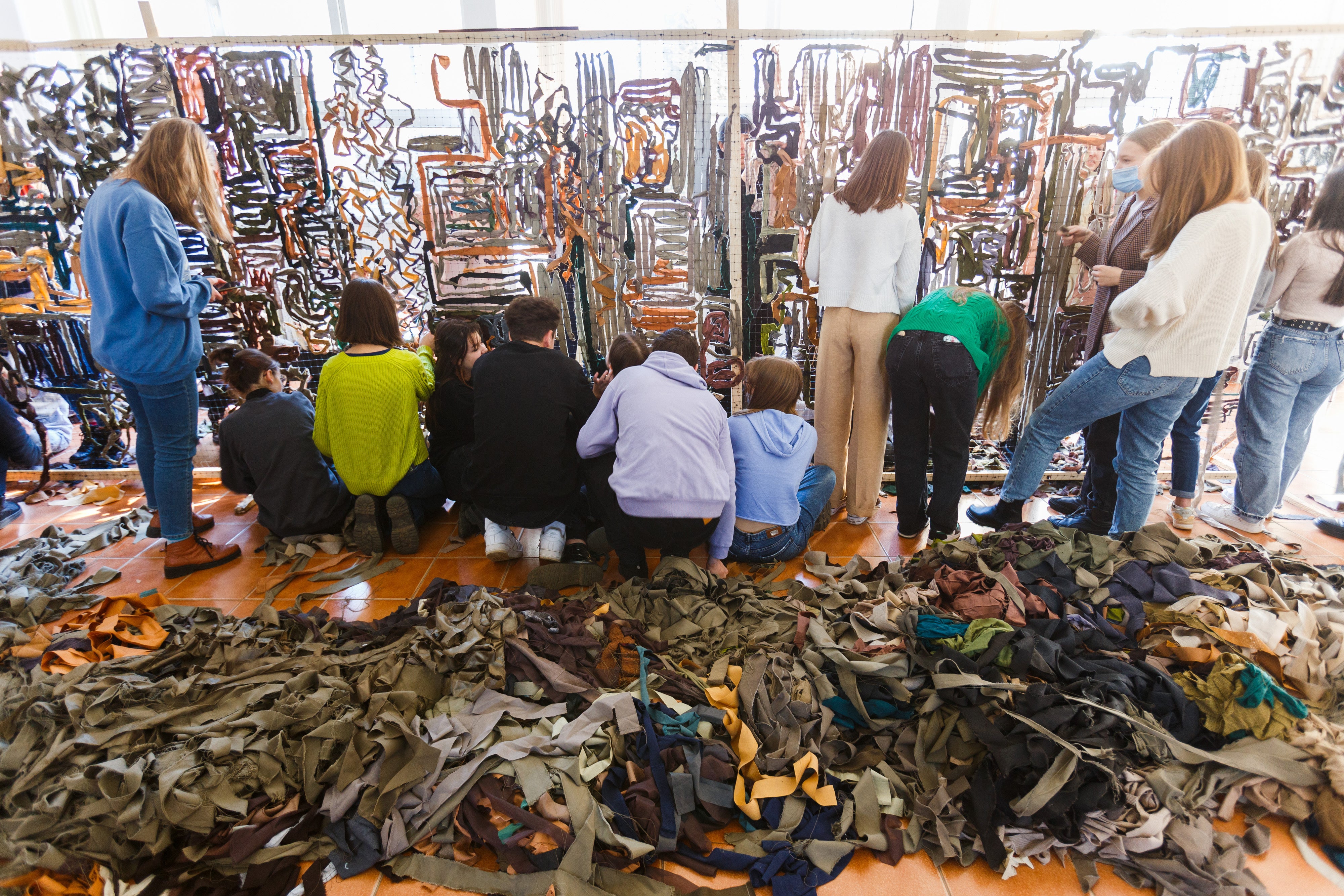 People work on a camouflage net for Ukrainian defenders