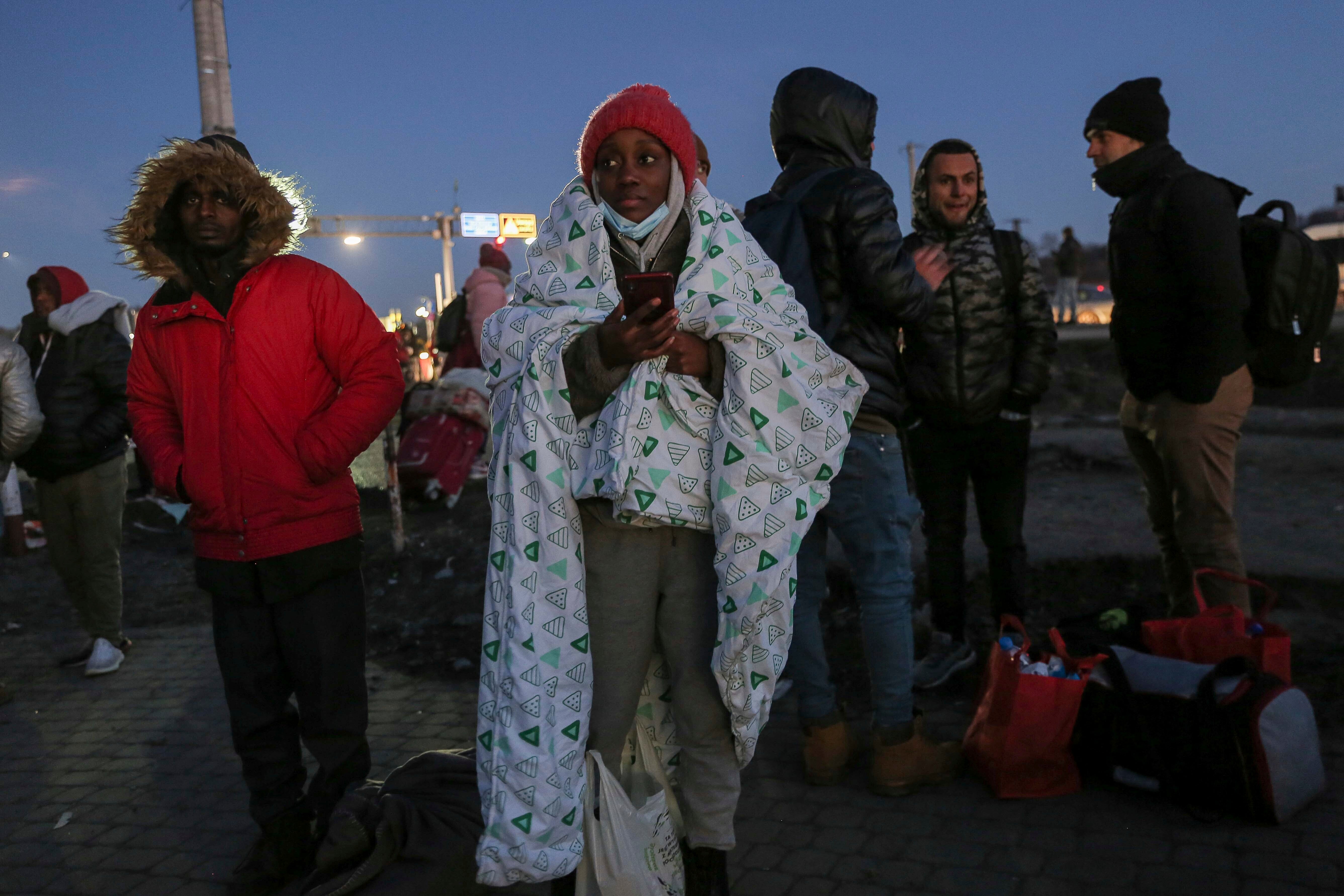 A student covers herself in blanket at the Medyka border crossing, Poland