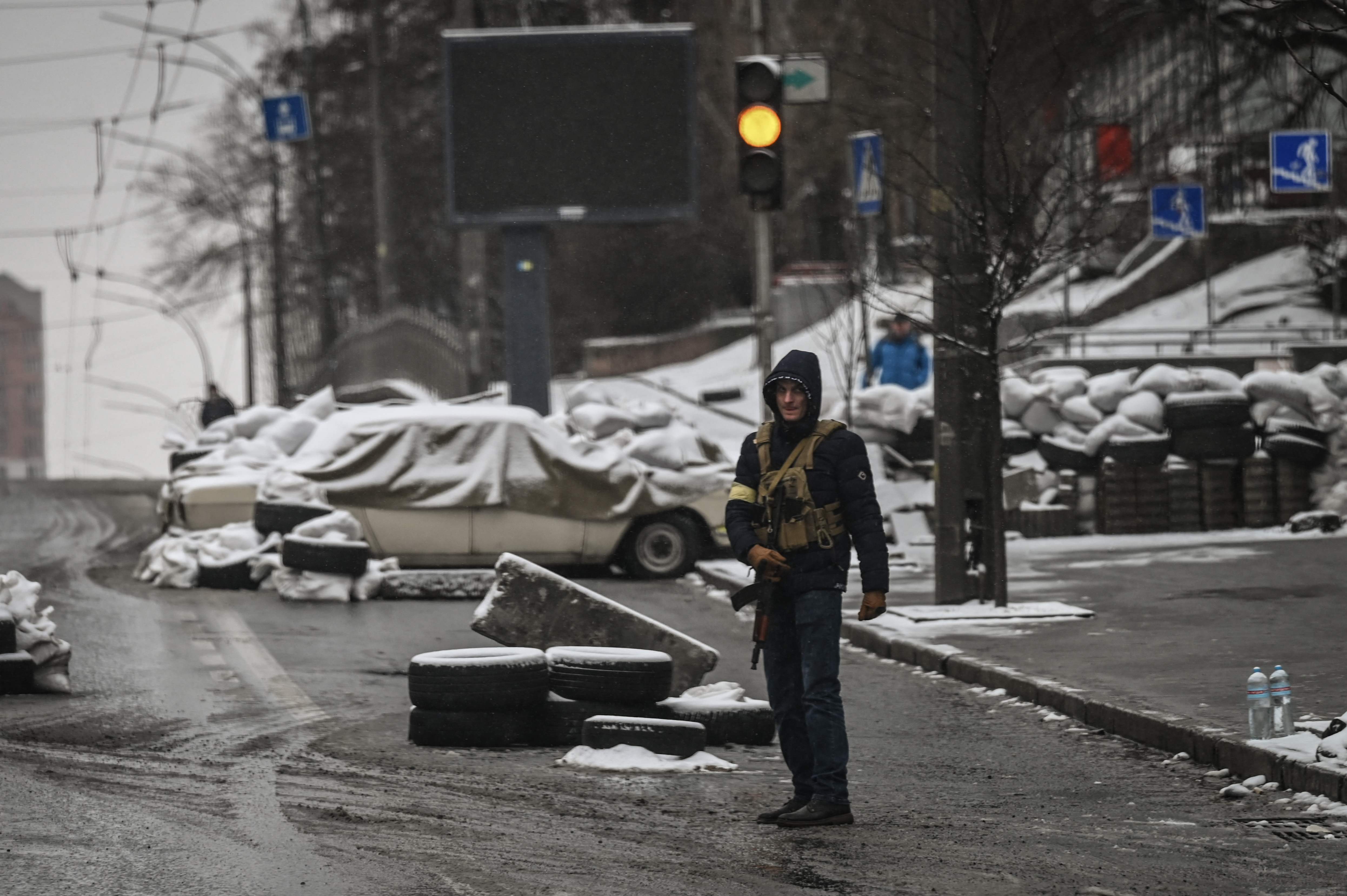 An armed man stands at a roadblock in downtown Kyiv on Tuesday as the city faces more attacks from Russian forces