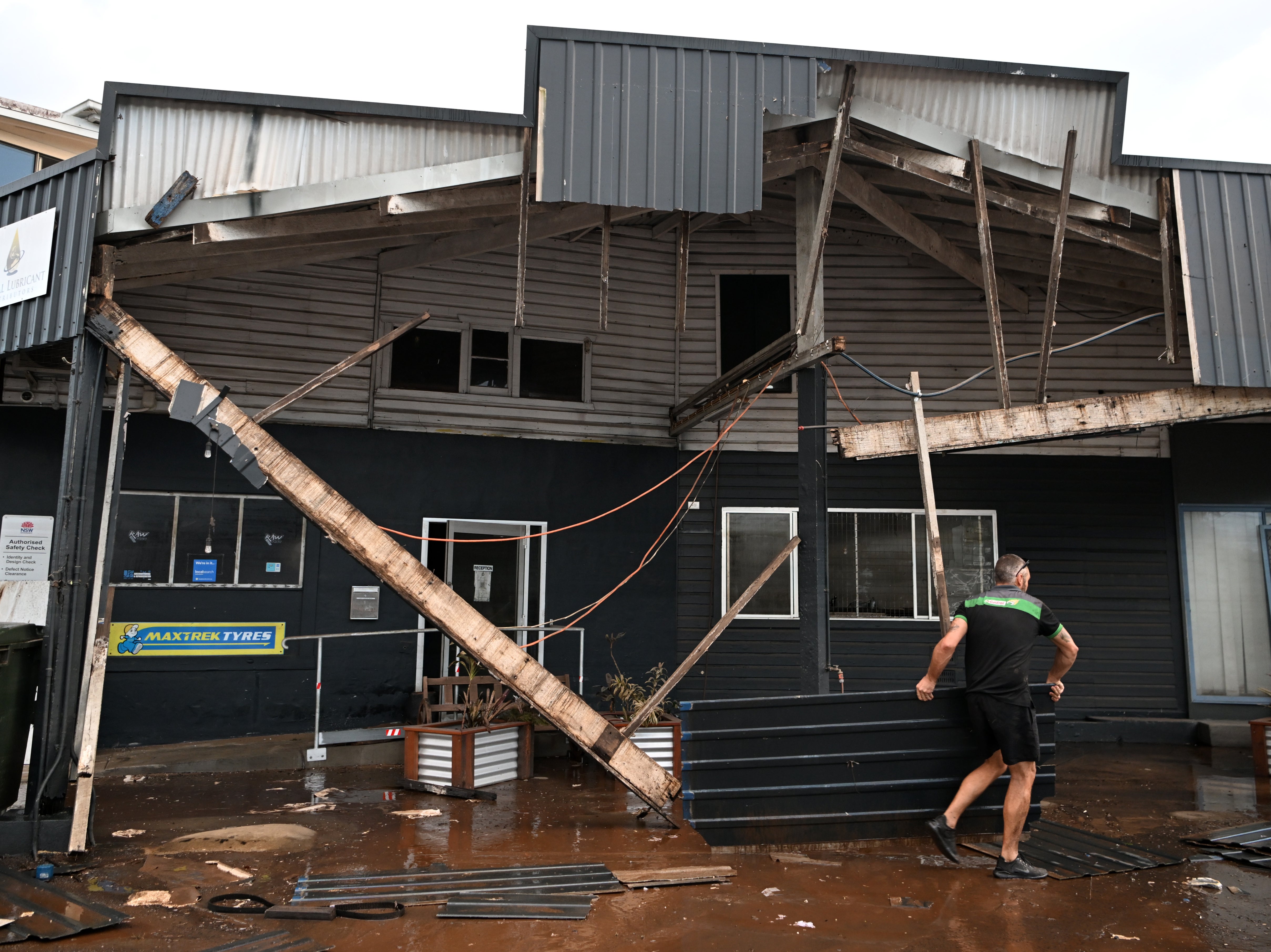 Grant McPherson removes debris from his flood-affected car mechanic business in Lismore