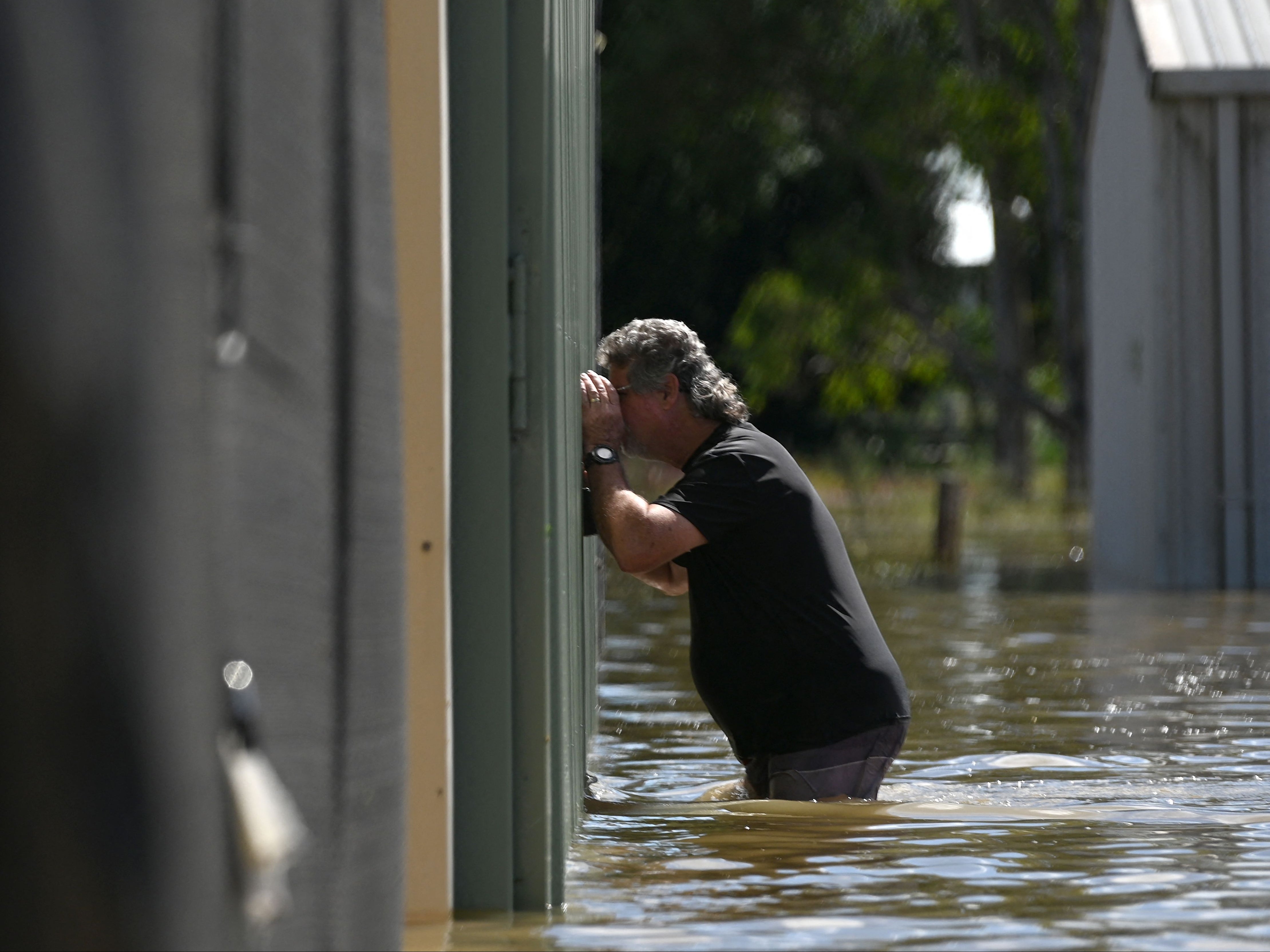 A man checks the condition of his aircraft inside a flooded hanger at an air strip in Grafton