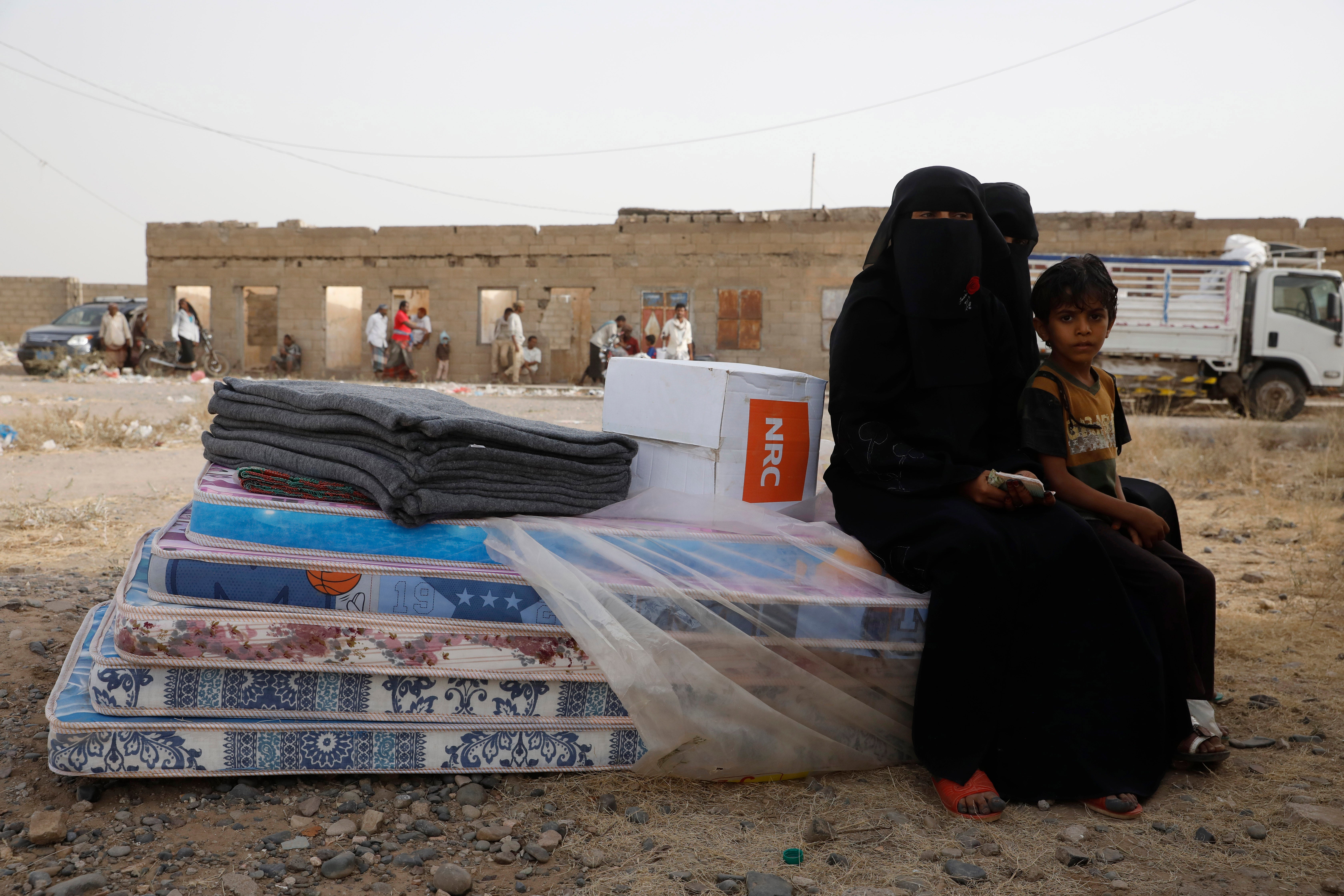 Two women and a child sit on mattresses and receive aid in the port province of Hodeidah, Yemen, 10 February