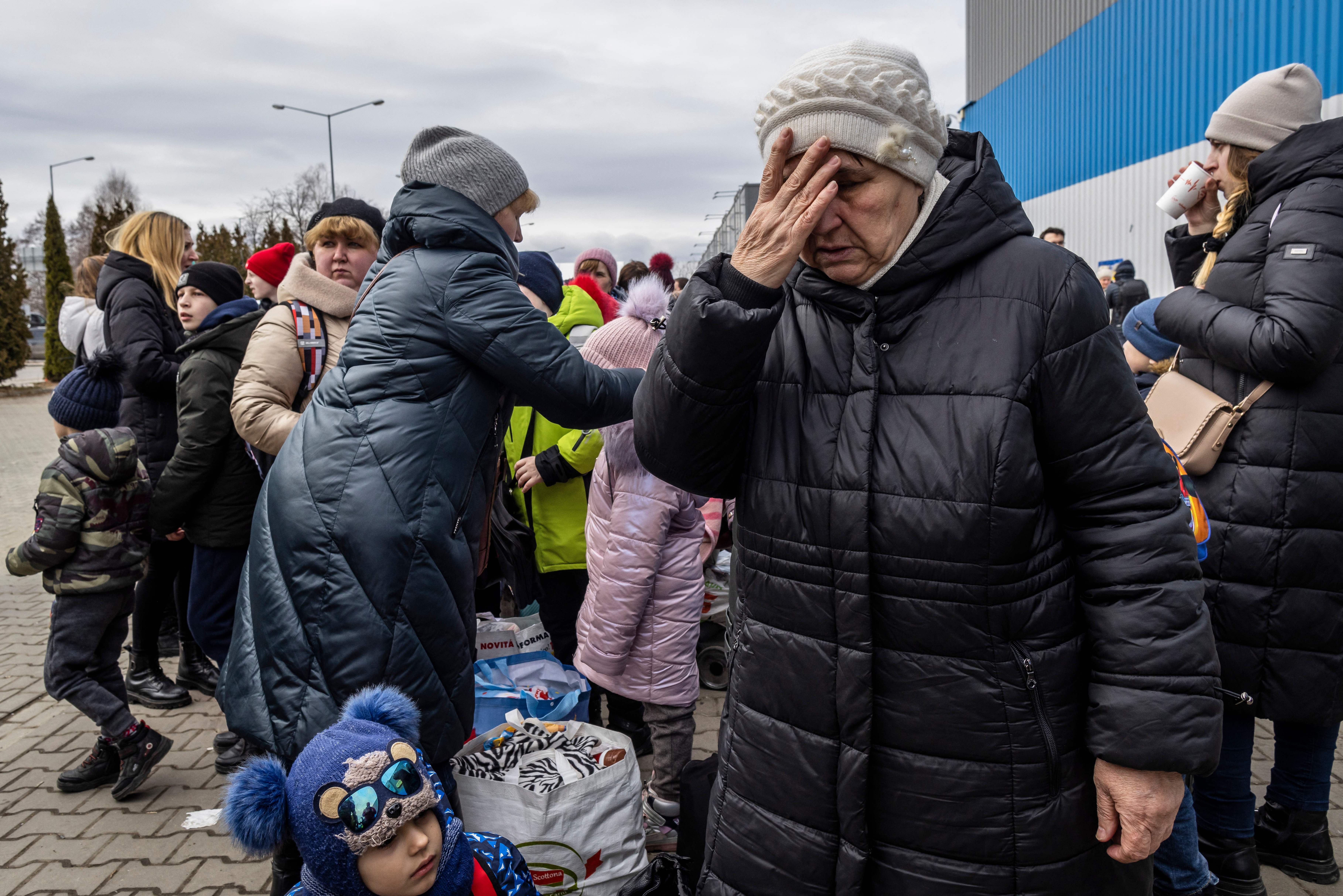 Ukrainian refugees stand outside a Temporary Reception Centre in Korczowa, Poland, 2 March 2022