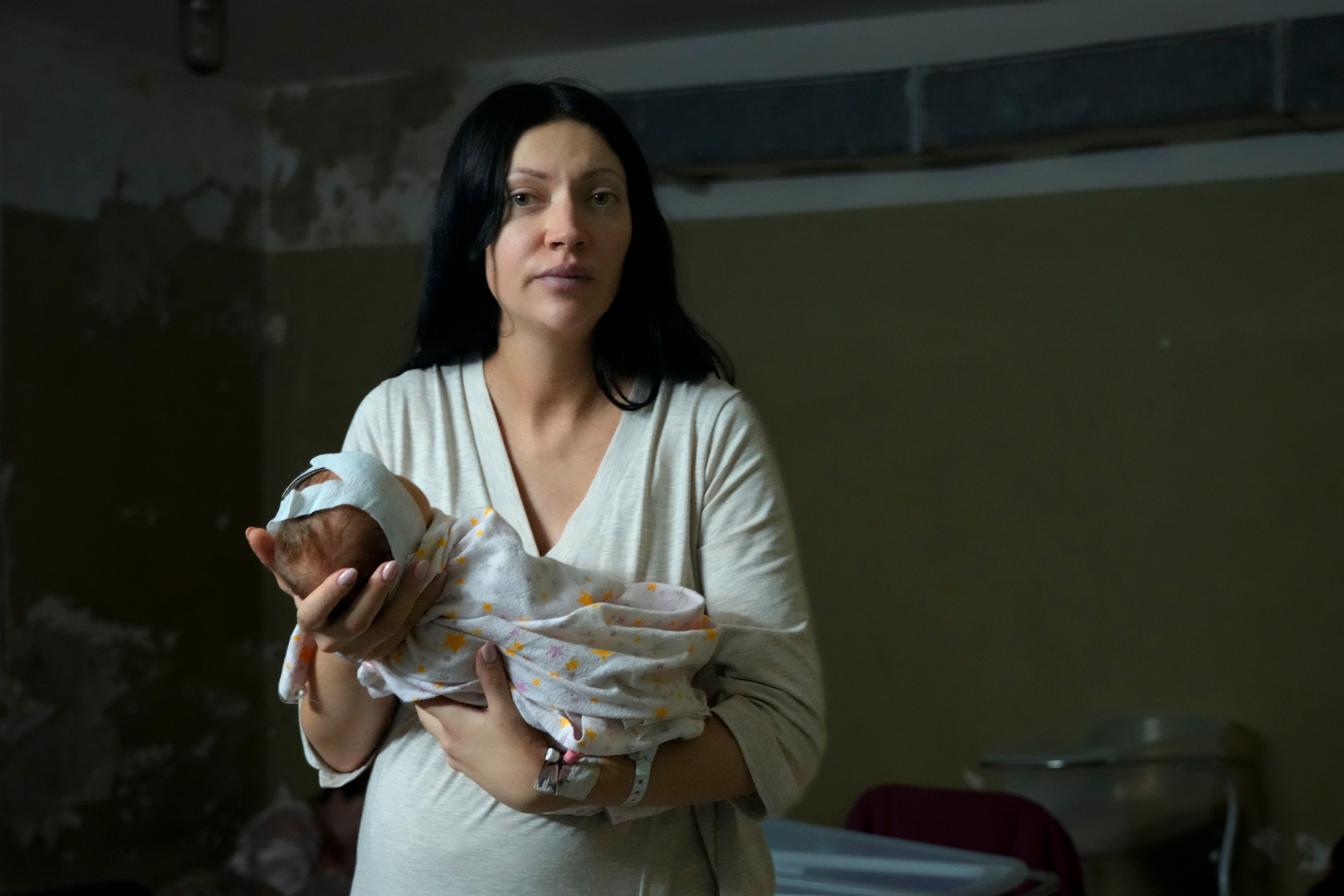 A woman, who did not want to be identified, poses for a photograph as she holds her newborn girl in the basement of a maternity hospital converted into a medical ward and used as a bomb shelter during air raid alerts, in Kyiv, Ukraine