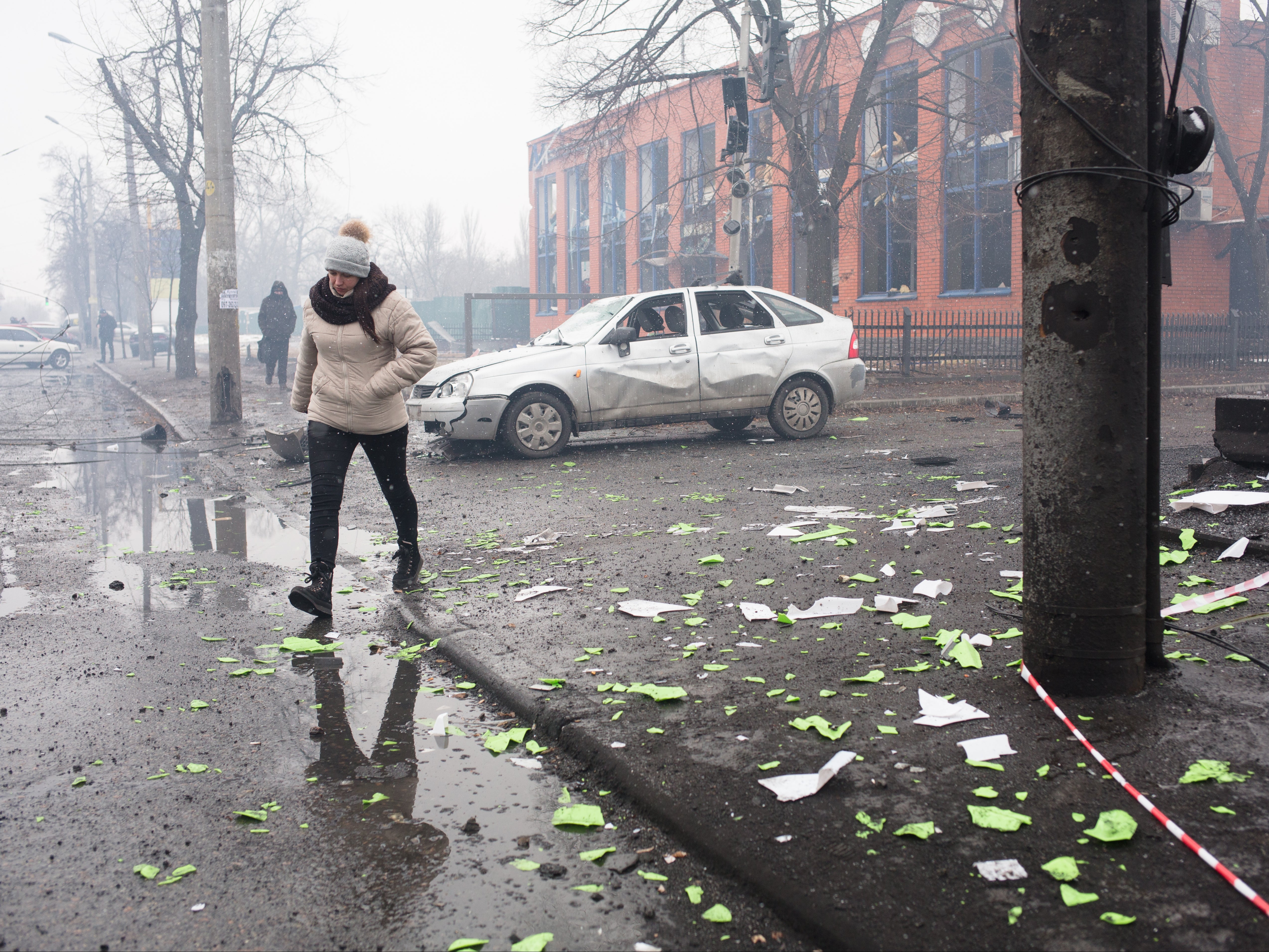 A woman walks by a shelled gym building in Kyiv, Ukraine