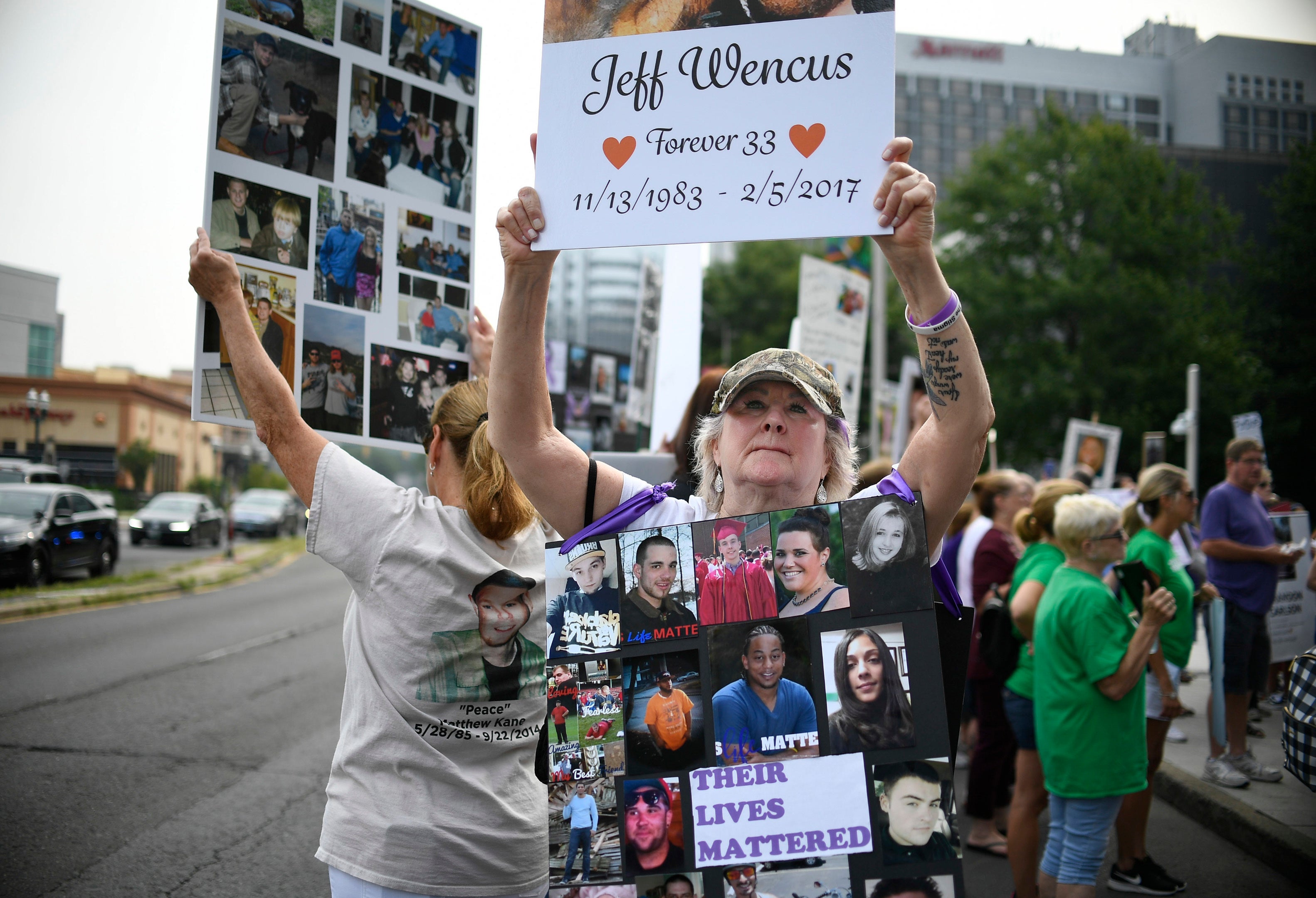 Lynn Wencus of Wrentham, Mass, holds a sign for her son Jeff during a protest at Purdue Pharma headquarters in Stamford, Conn, in 2018