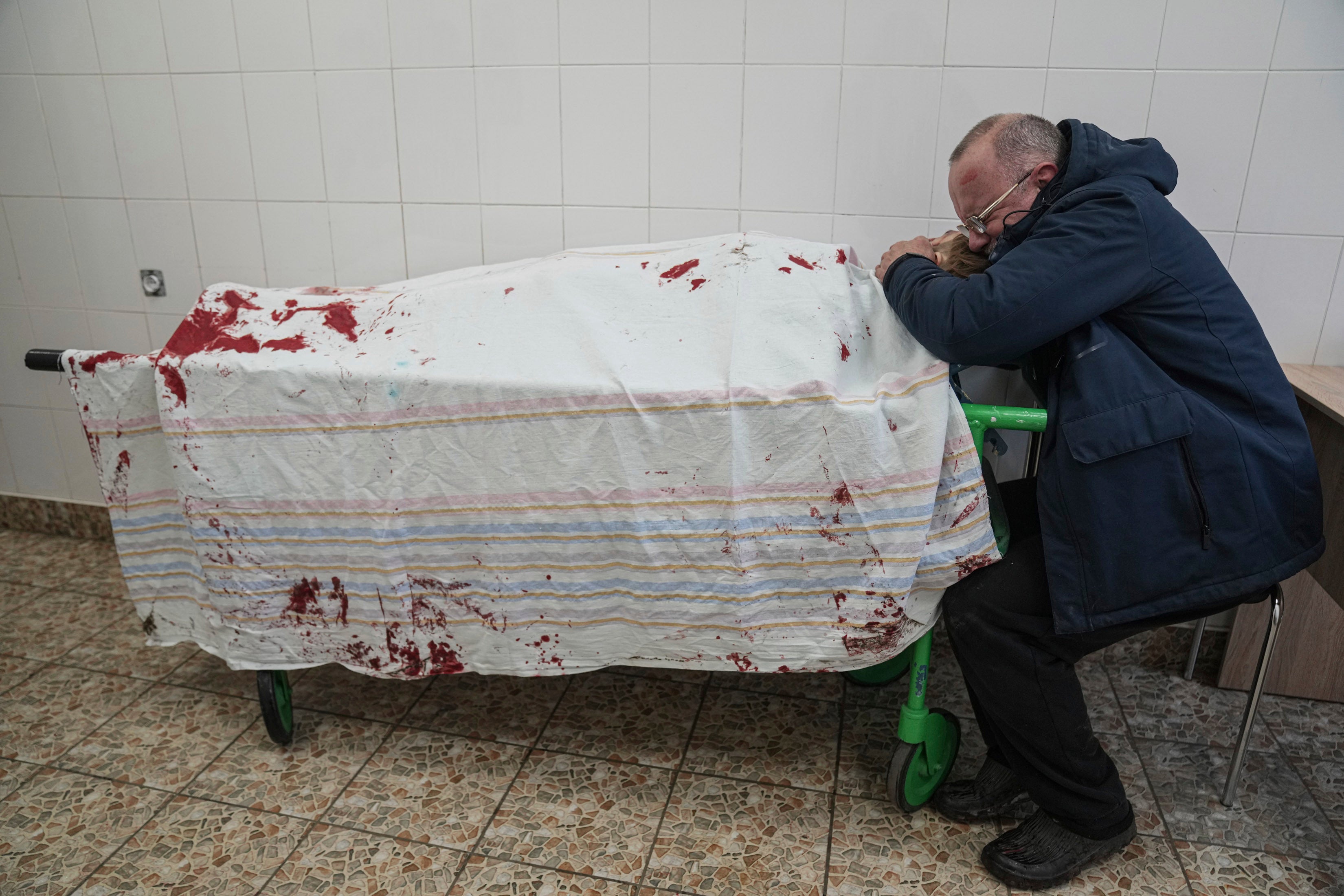 The father of a teenager cries on his son’s lifeless body lying on a stretcher