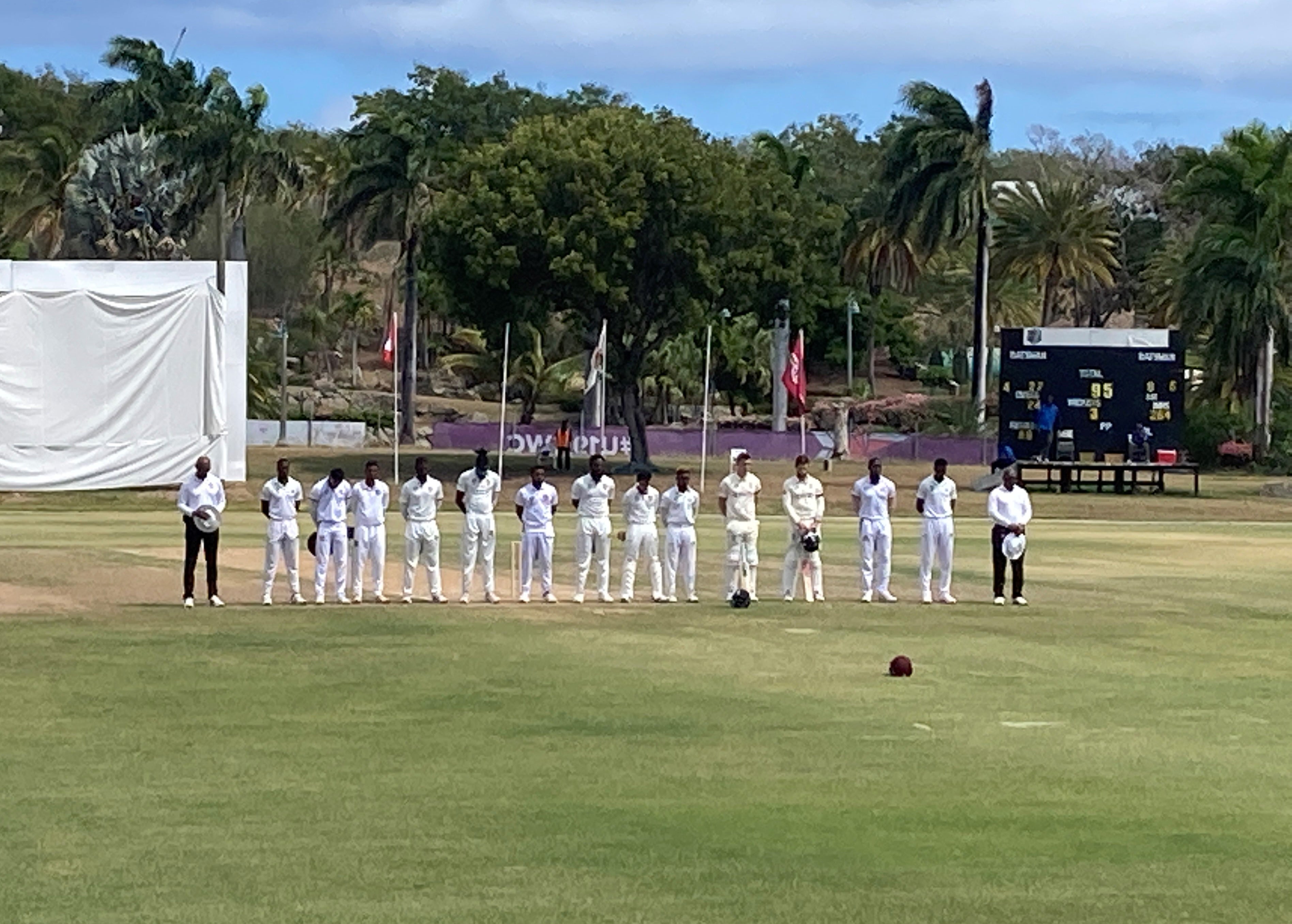 England batters Dan Lawrence and Ben Foakes stand with Cricket West Indies President’s XI players during a moment of silence for Shane Warne