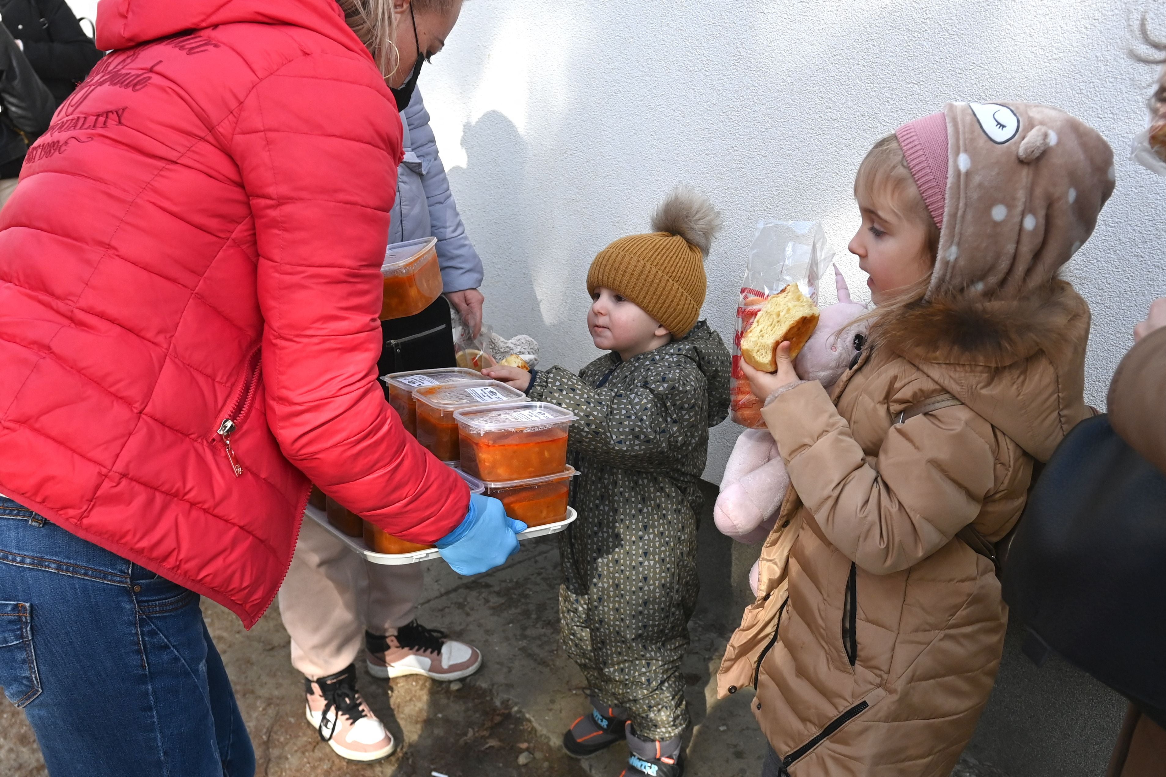 Ukrainian children receive food in front of a temporary refugee centre at a primary school in Tiszabecs close to the Hungarian-Ukrainian border