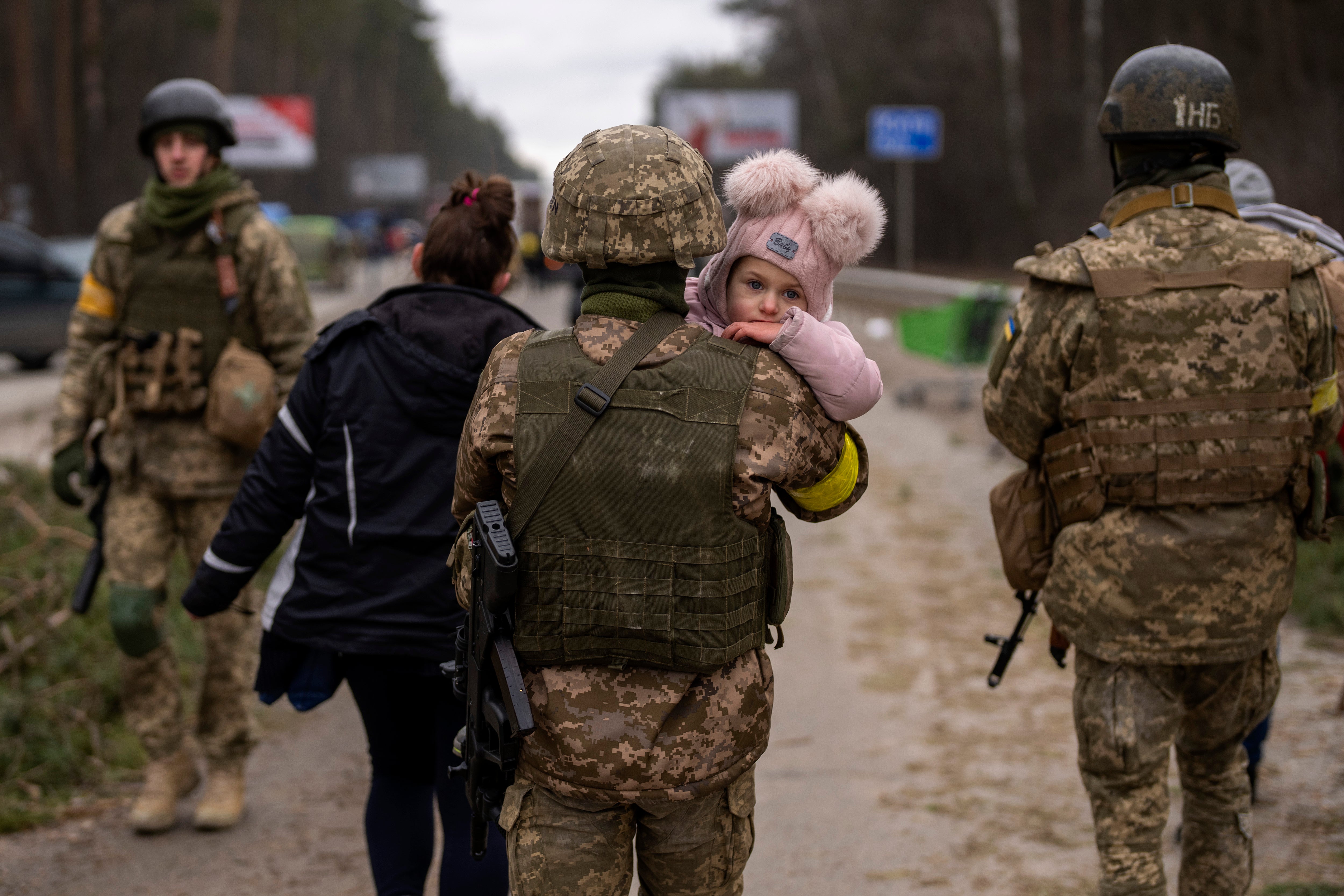 A Ukrainian soldier carries a baby fleeing with her family