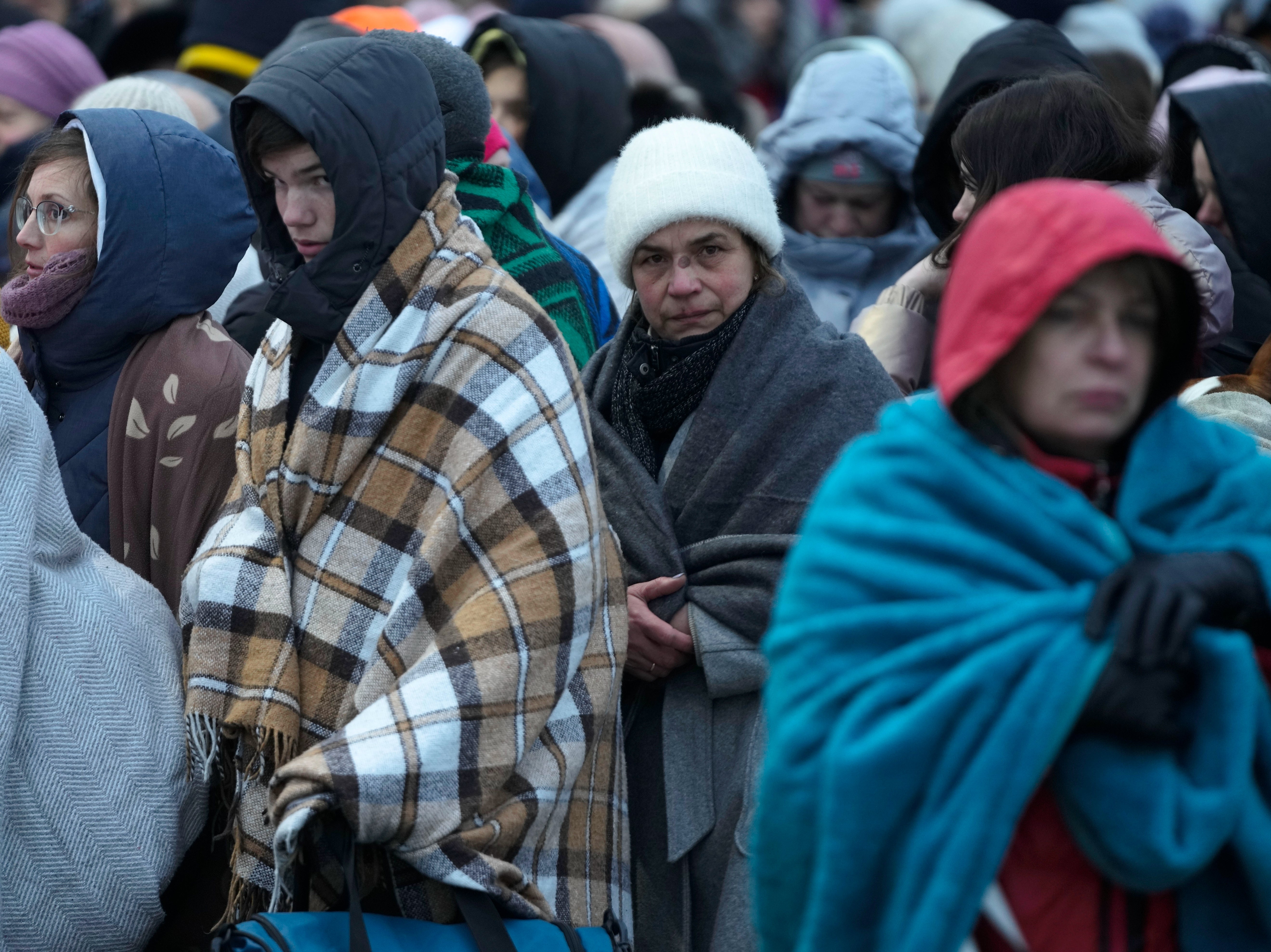 Refugees, mostly women and children, wait in a crowd for transportation after fleeing from the Ukraine and arriving at the border crossing in Medyka, Poland, 7 March 2022