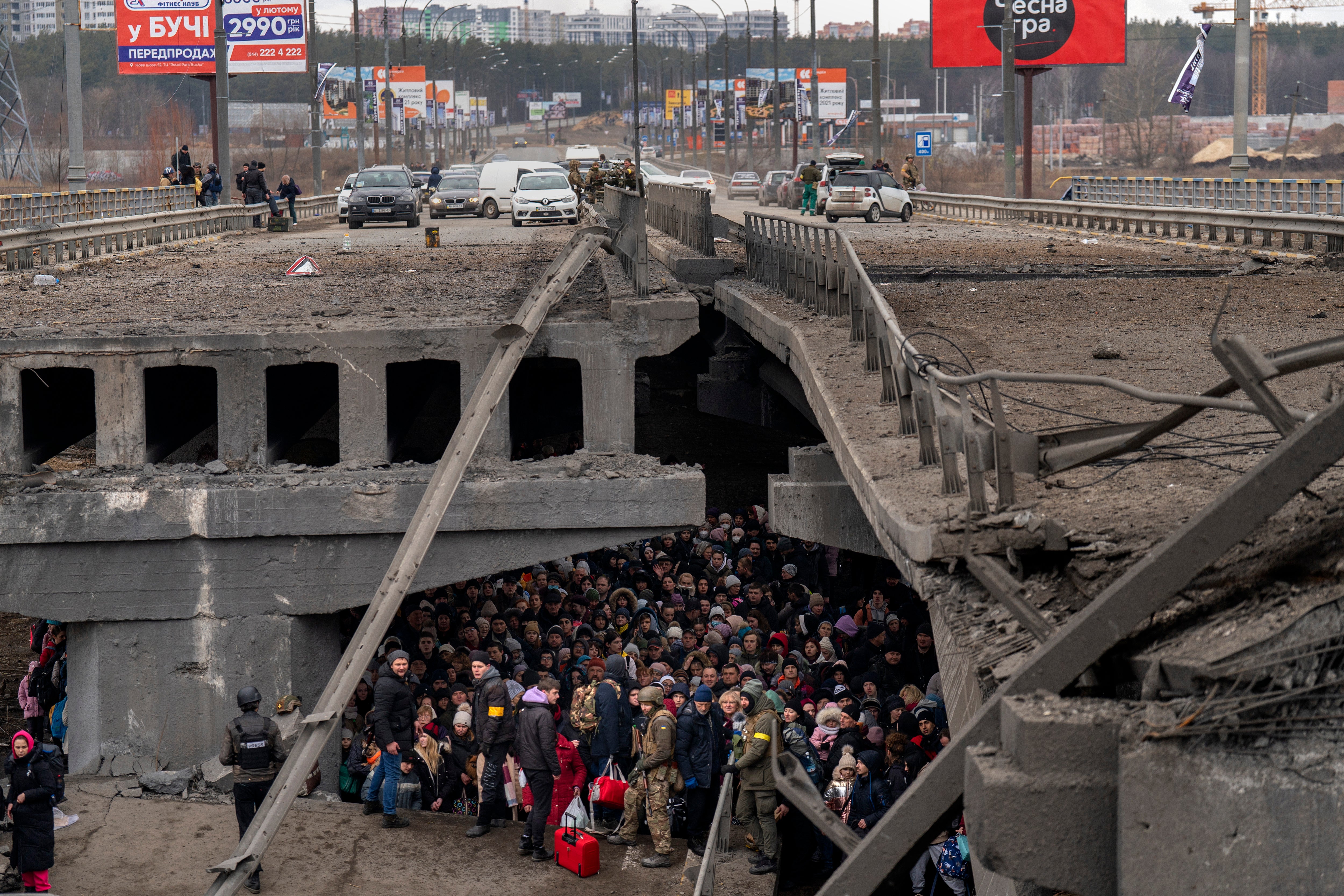 Ukrainians crowd under a destroyed bridge as they try to flee across the Irpin River.