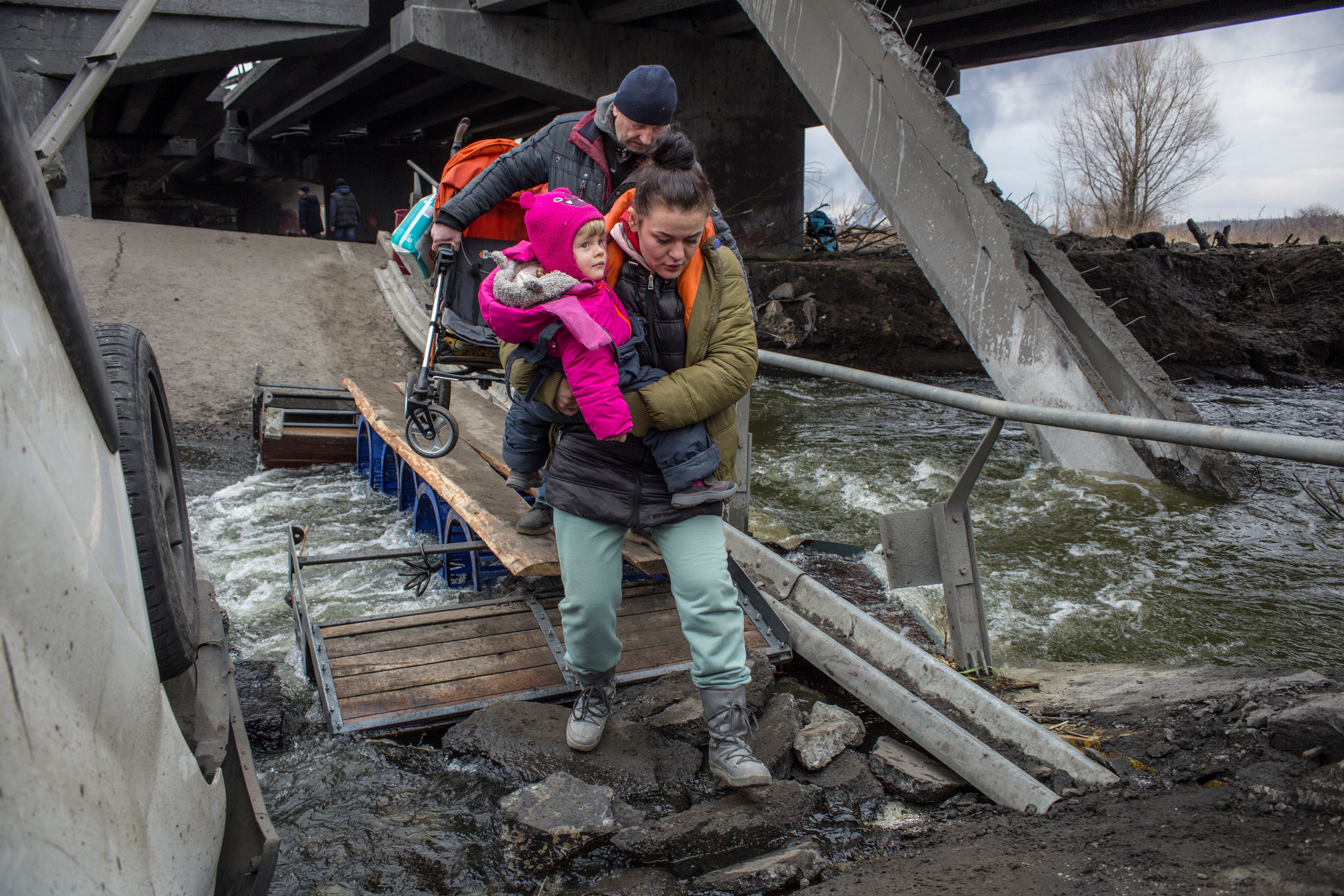 Civilians cross amid rubble of a damaged bridge in Irpin.