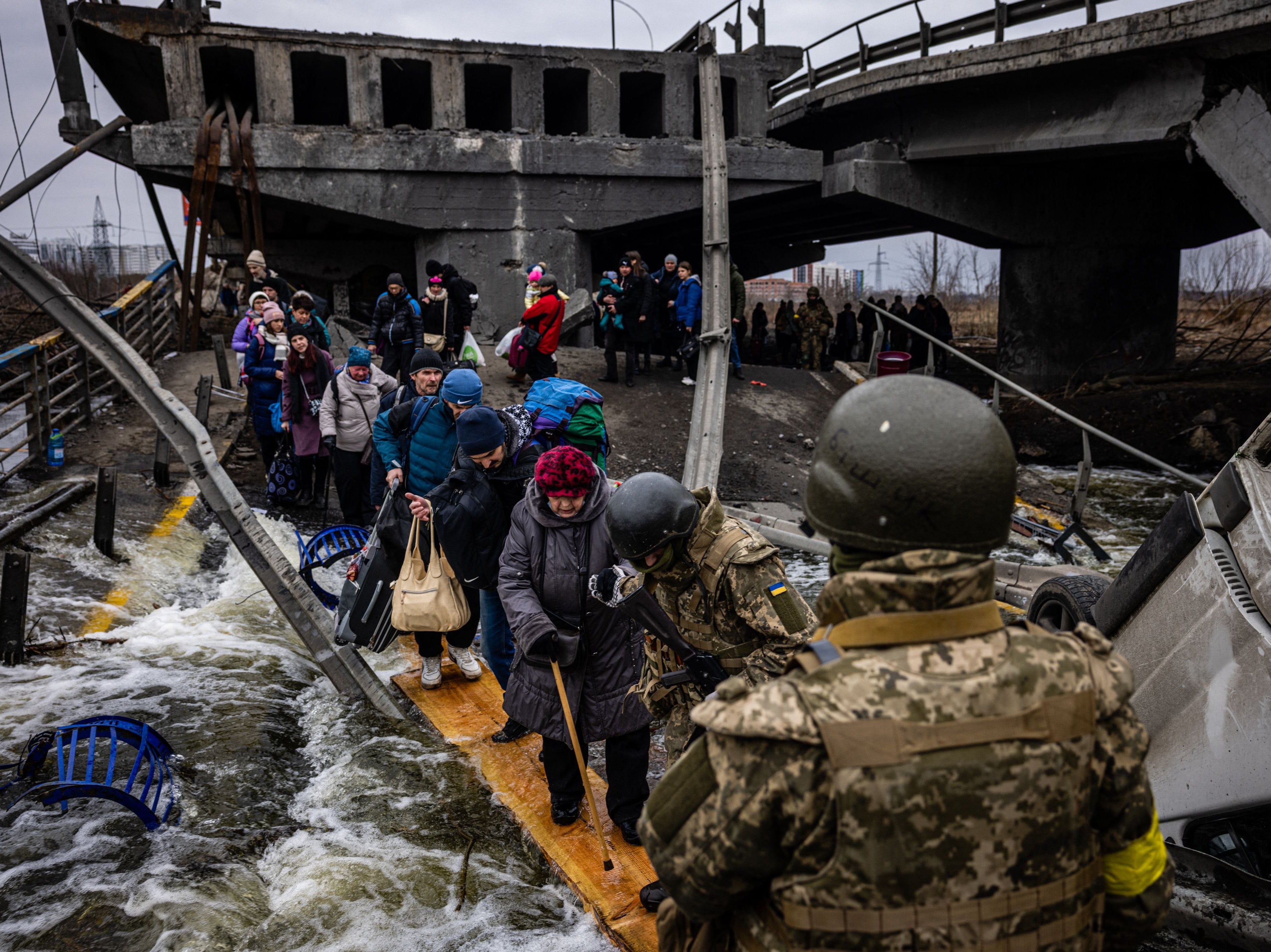 Evacuees cross a destroyed bridge as they flee the city of Irpin, northwest of Kyiv, 7 March 2022