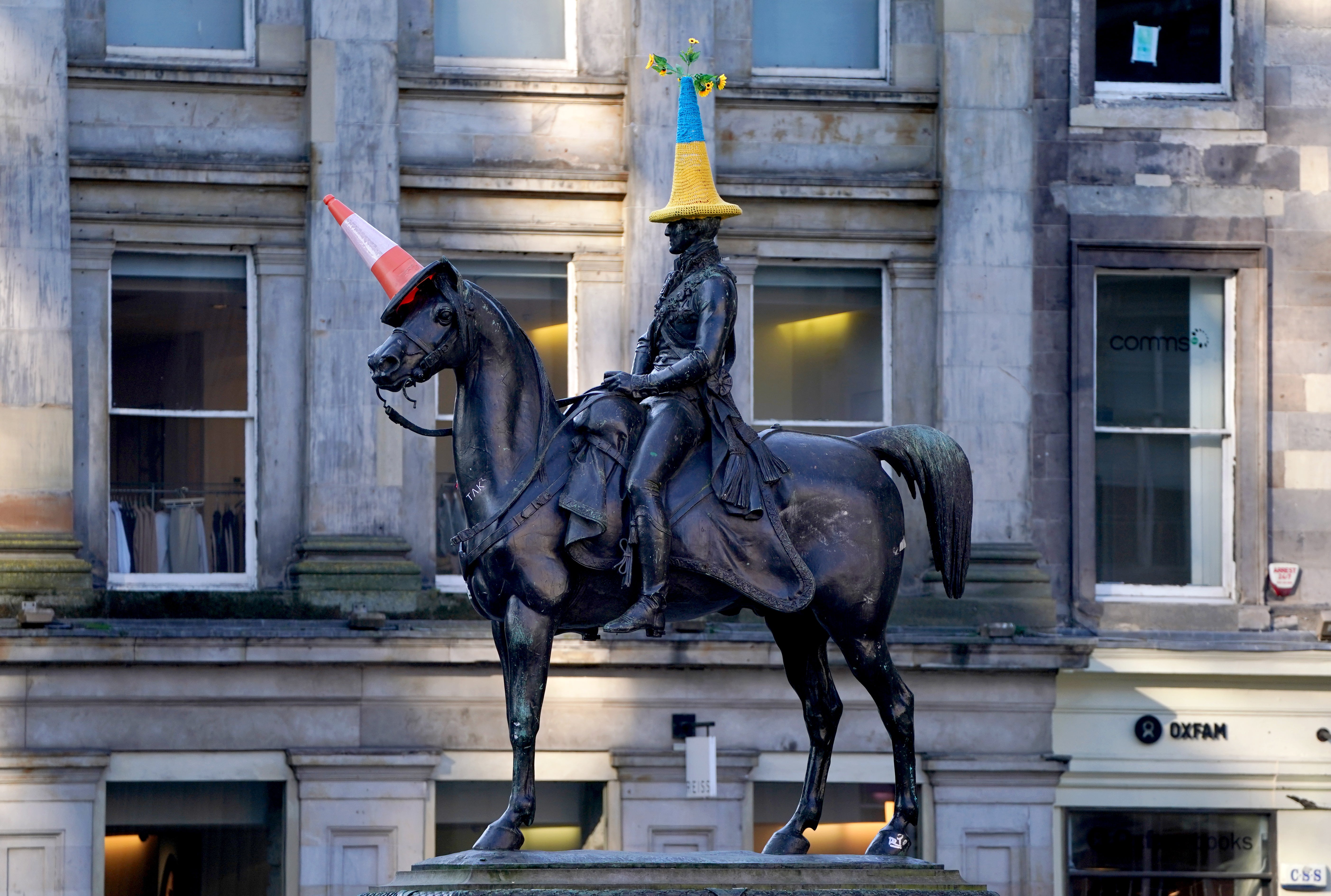 A traffic cone in the colours of the flag of Ukraine has been placed on top of the Duke of Wellington statue in Glasgow (Andrew Milligan/PA)