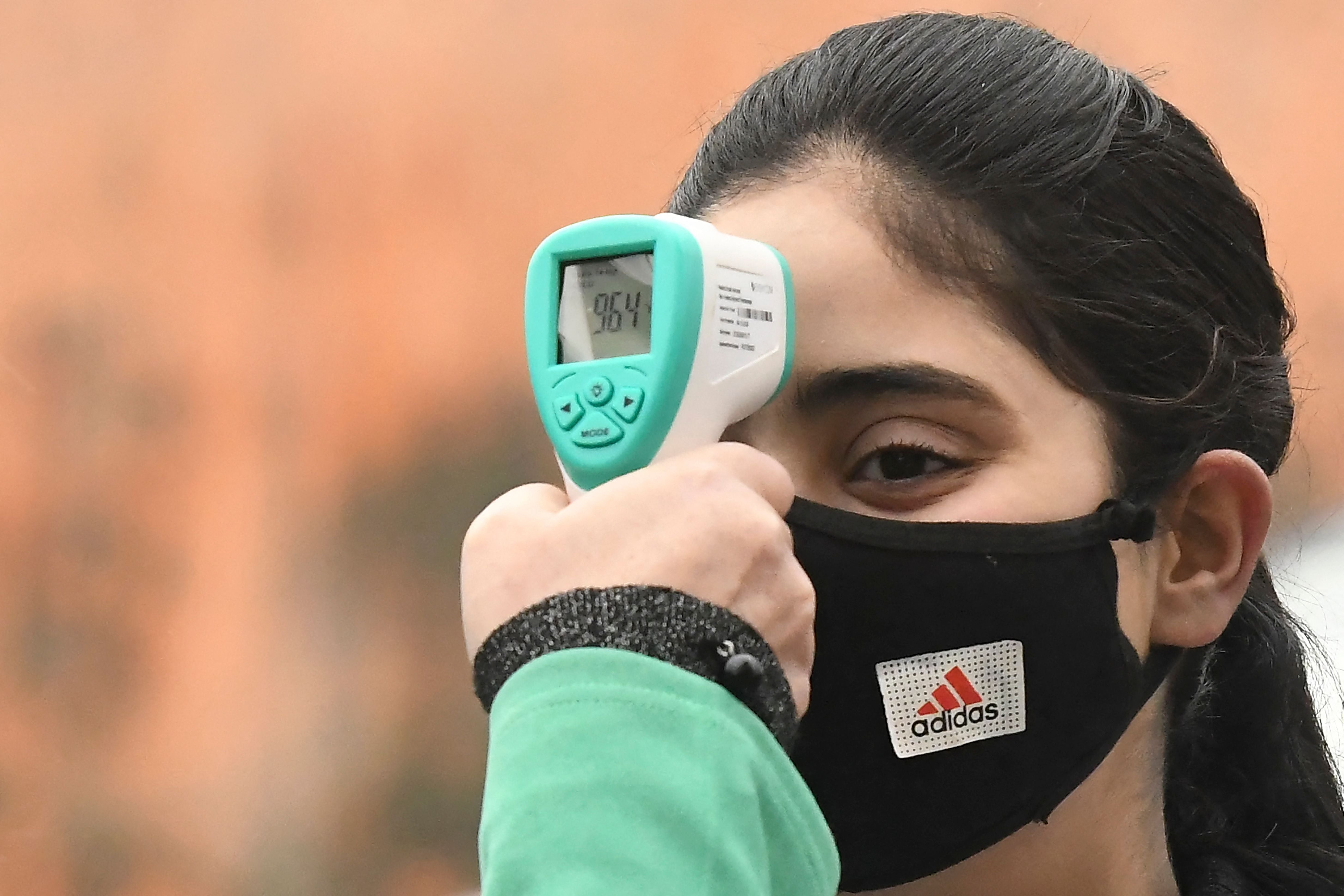 A nurse checks the temperature of students in Kashmir, India