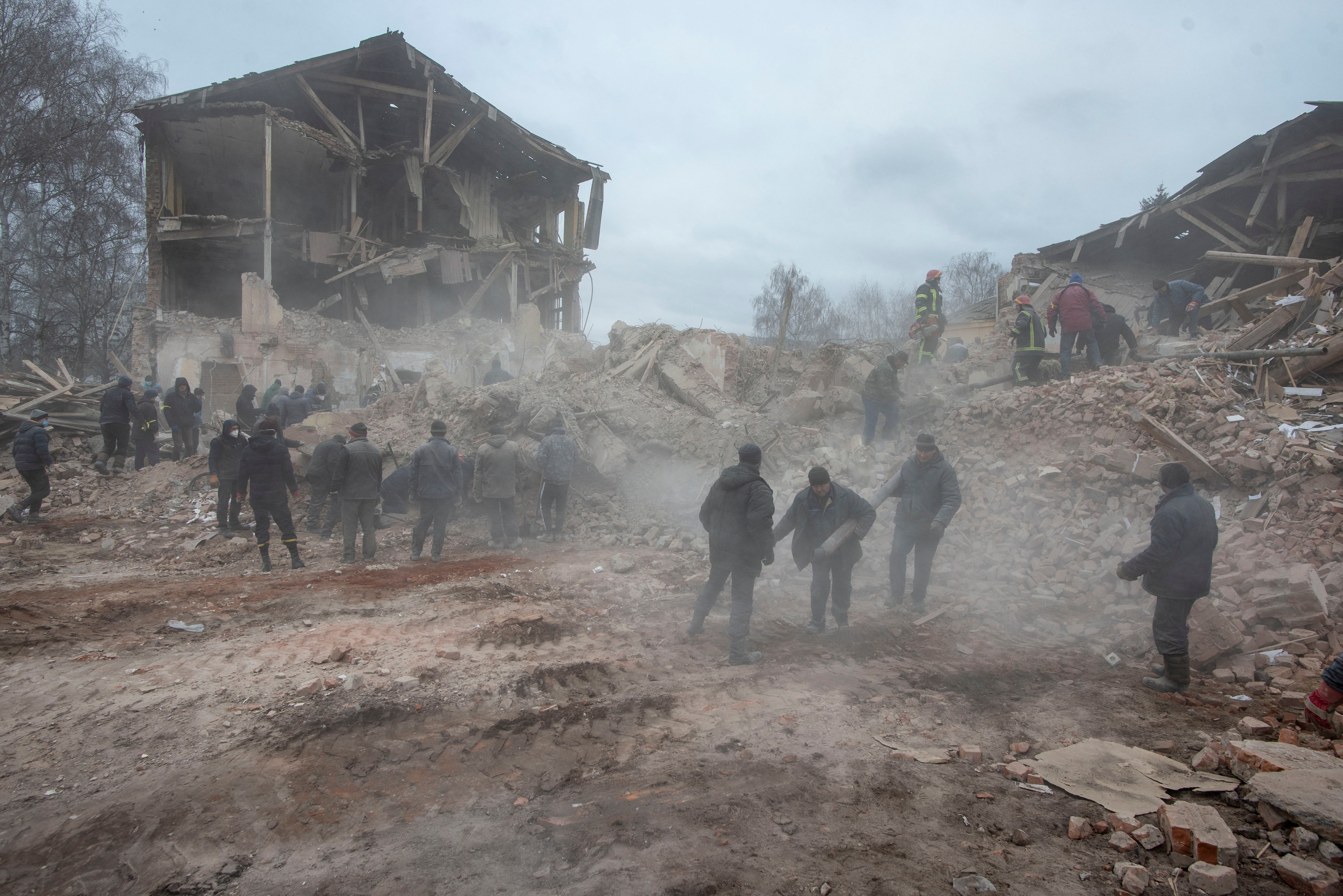 People remove debris at the site of a military base building that, according to the Ukrainian ground forces, was destroyed by an air strike, in the town of Okhtyrka in the Sumy region