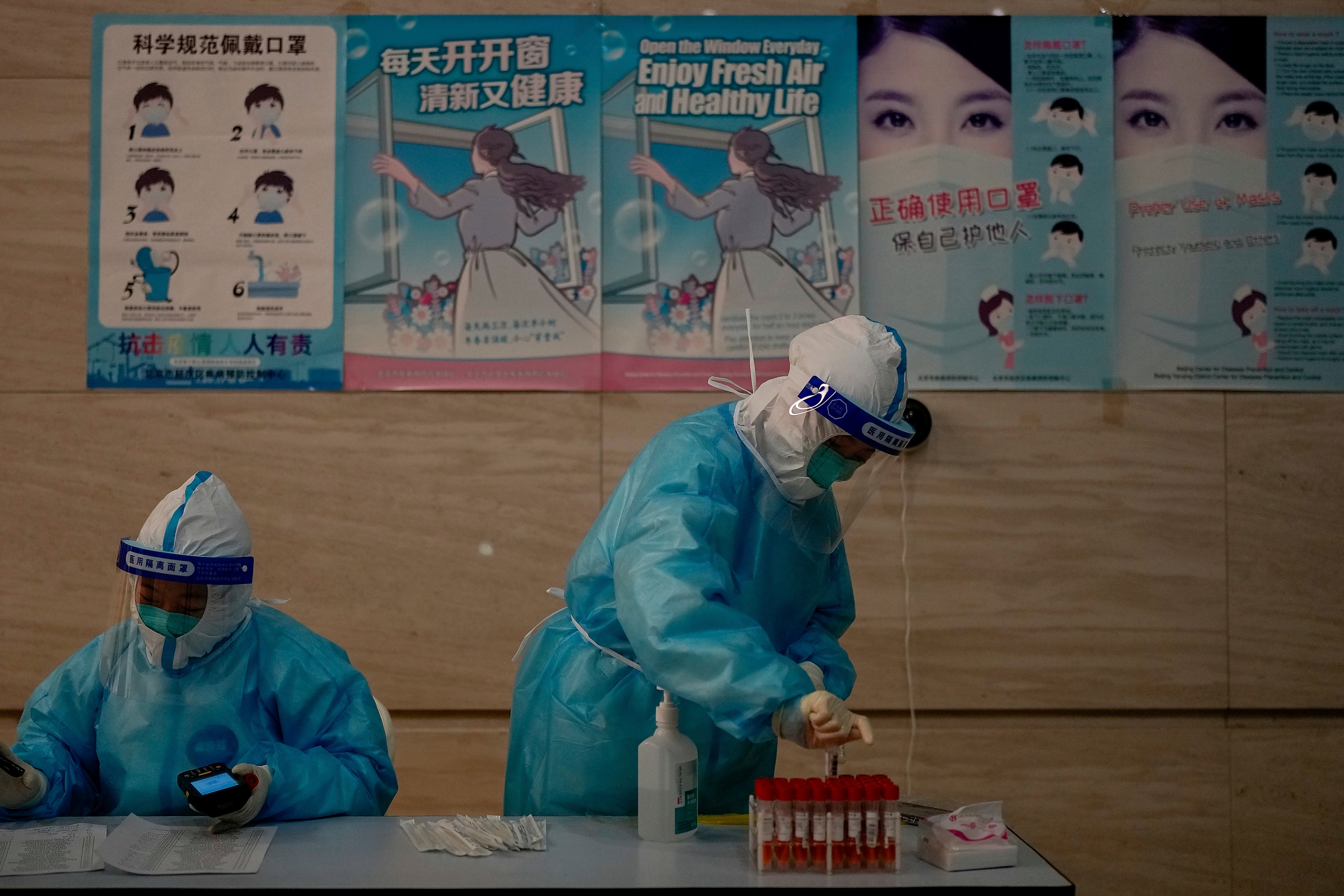 Health workers wear protective clothing in Beijing where the virus has resurged