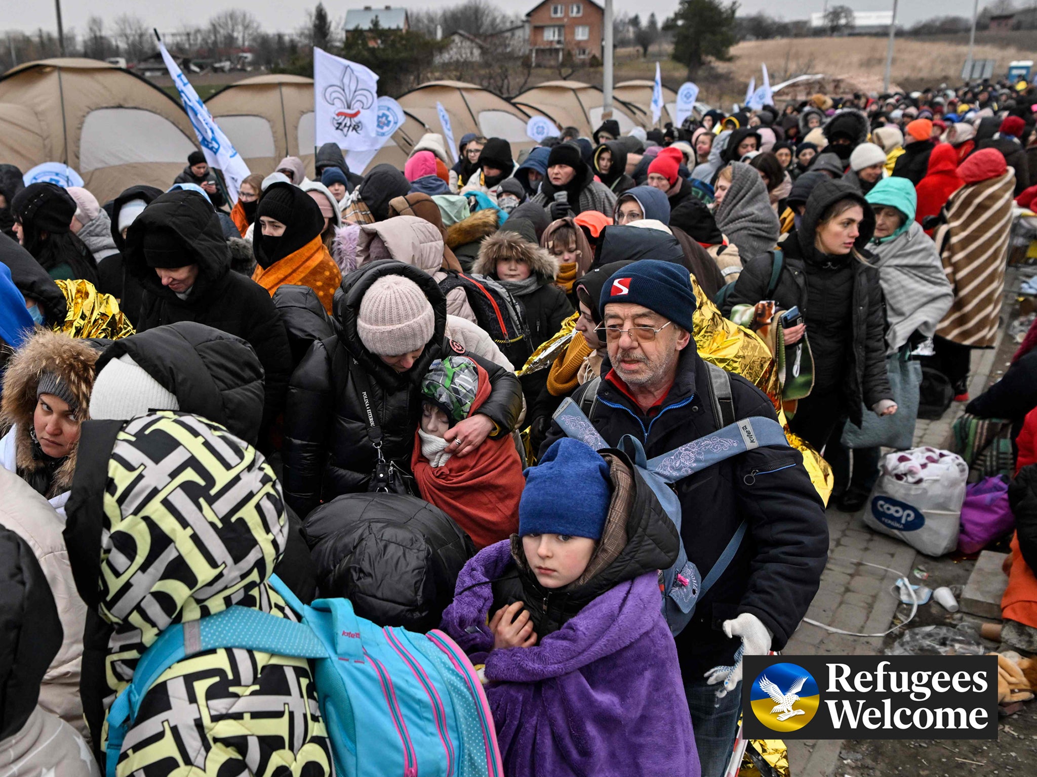 Refugees stand in line in the cold as they wait to be transferred to a train station after crossing the Ukrainian border into Poland, 7 March 2022