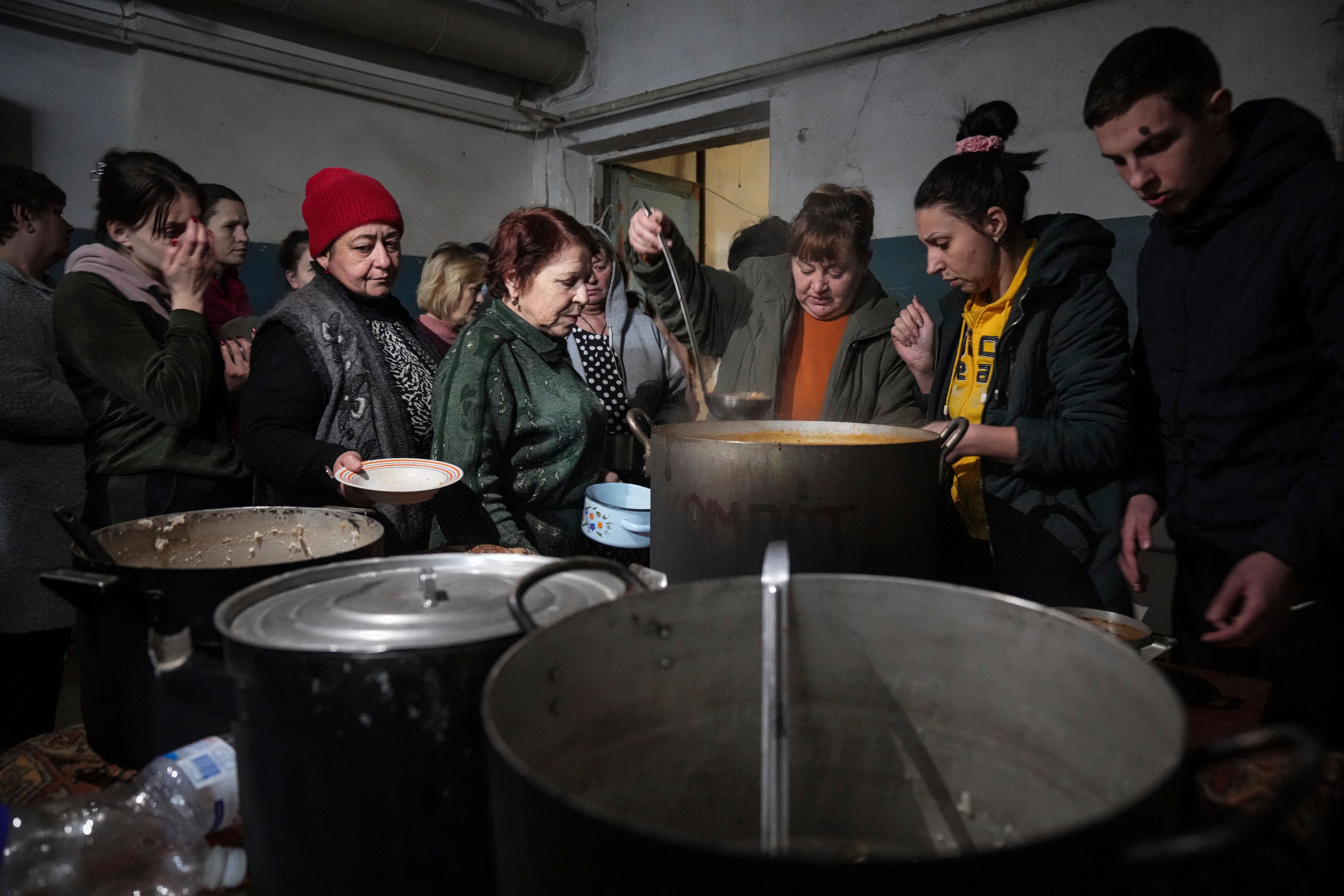 People queue to receive hot food in the improvised bomb shelter in Mariupol