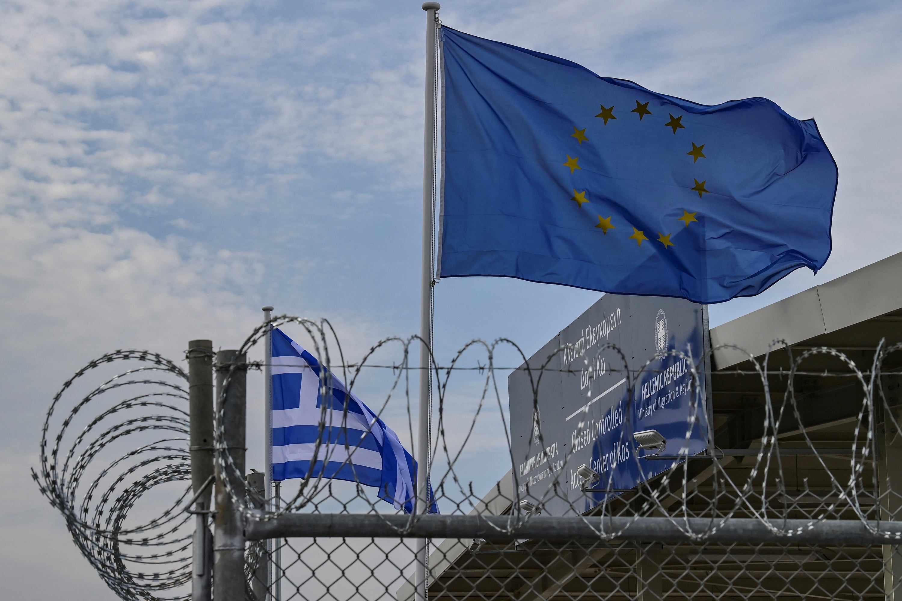 File photo: A European Union flag waves behind barbwires at the new closed center for migrants in the Greek island of Kos, 27 November 2021