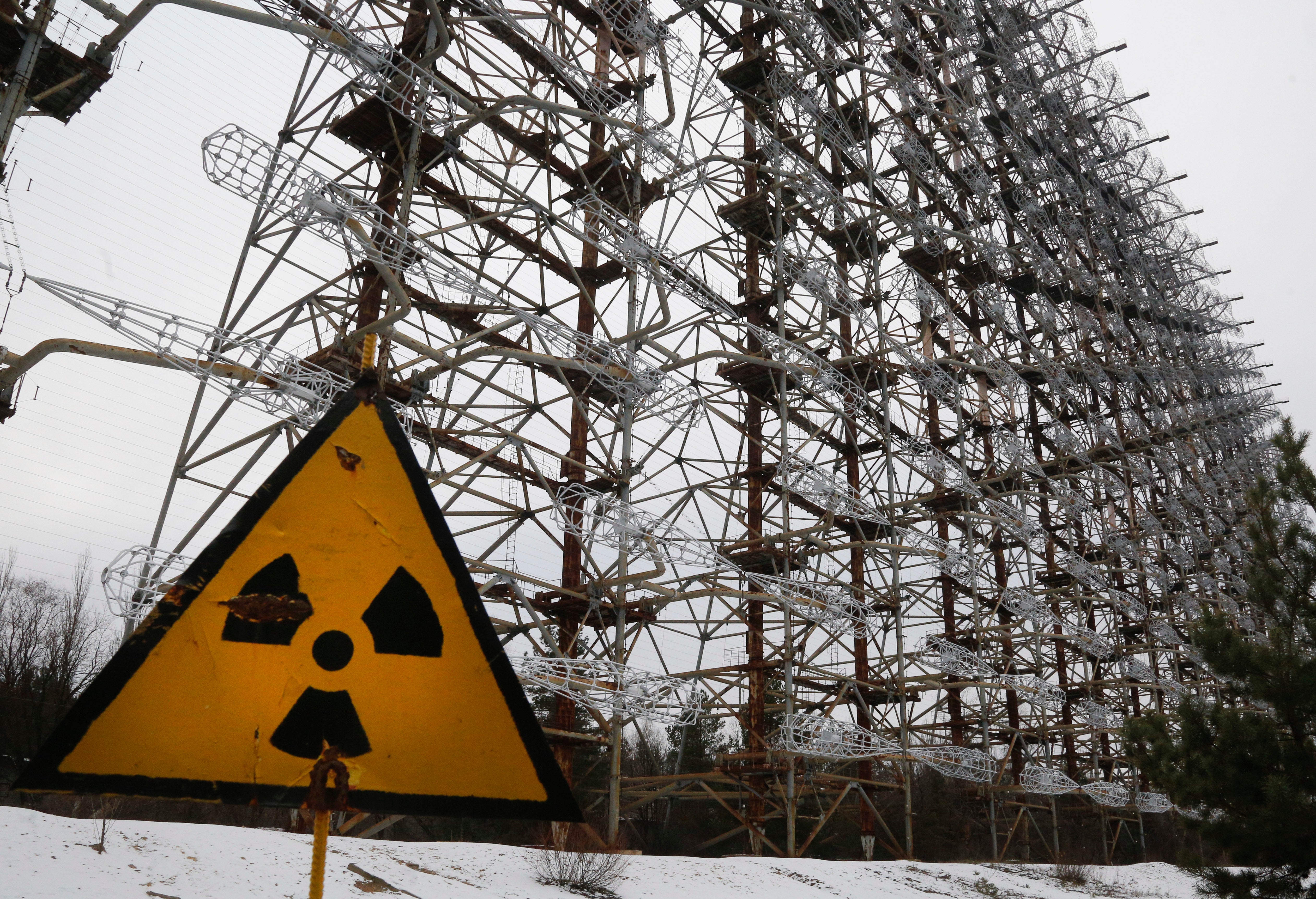 A Soviet-era top secret object Duga, an over-the-horizon radar system once used as part of the Soviet missile defense early-warning radar network, seen behind a radioactivity sign in Chernobyl