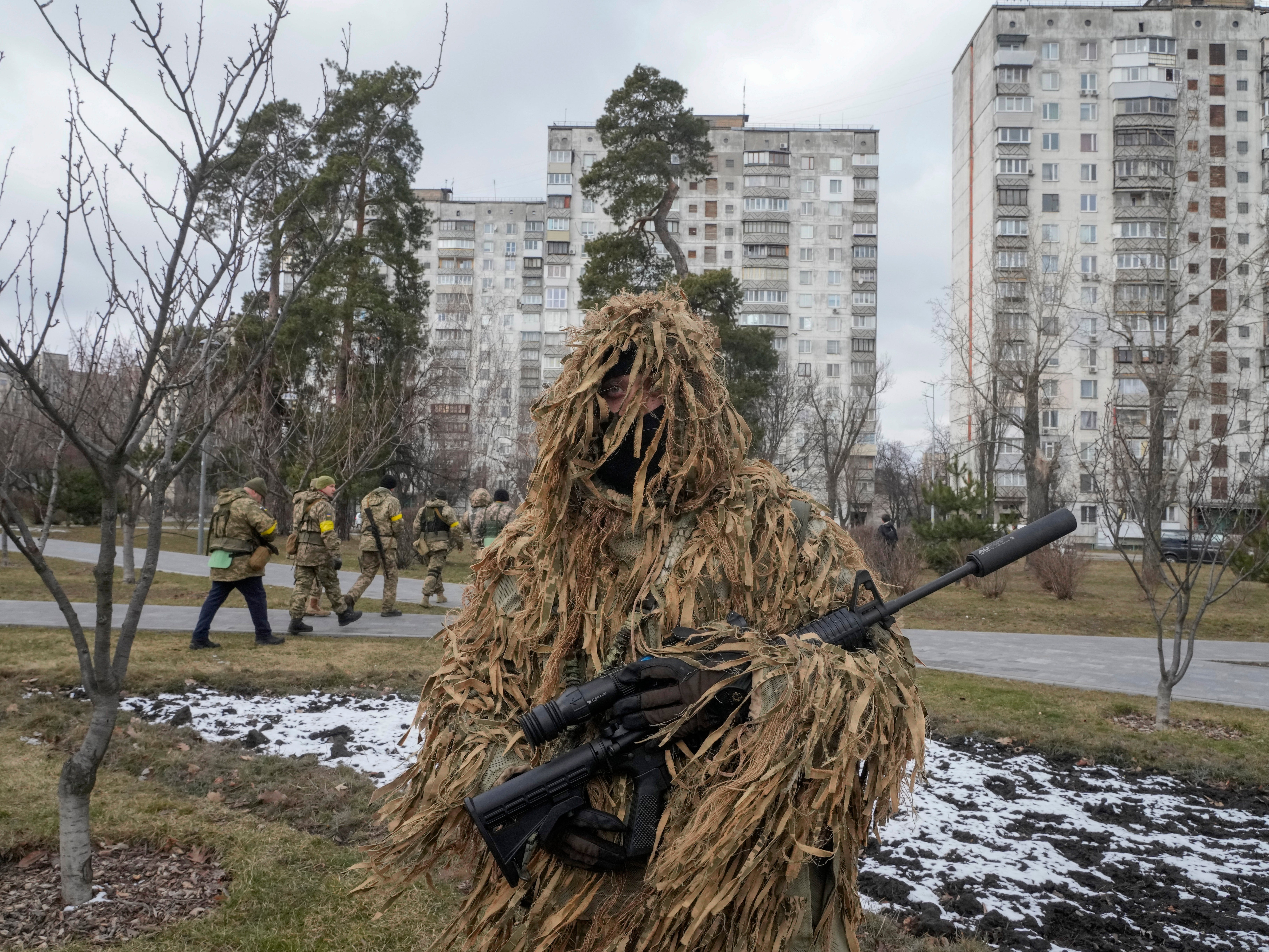 Ukrainian Territorial Defence Forces members and a camouflaged soldier near Kyiv