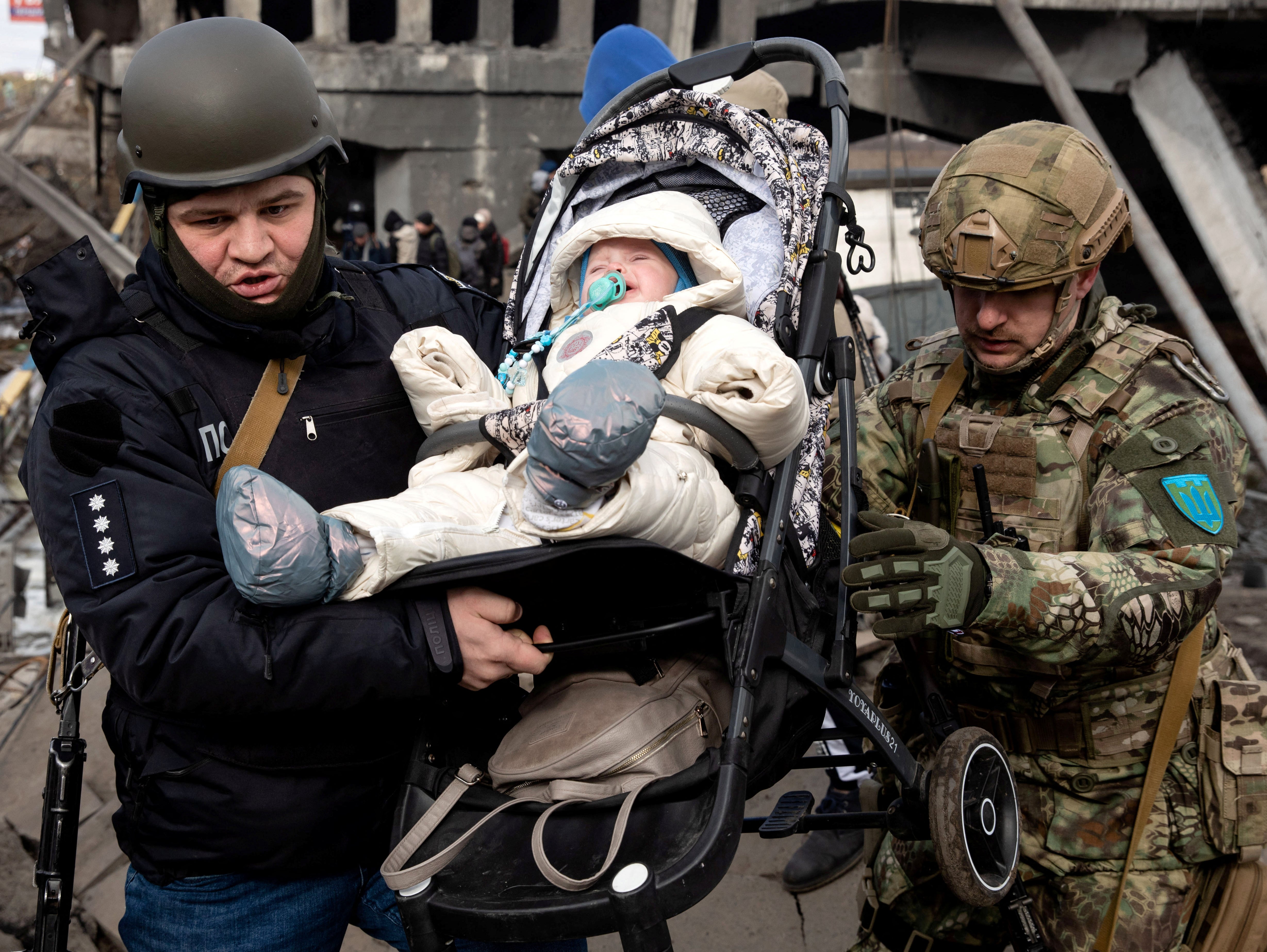 A baby is carried from rubble as people flee Irpin near Kyiv