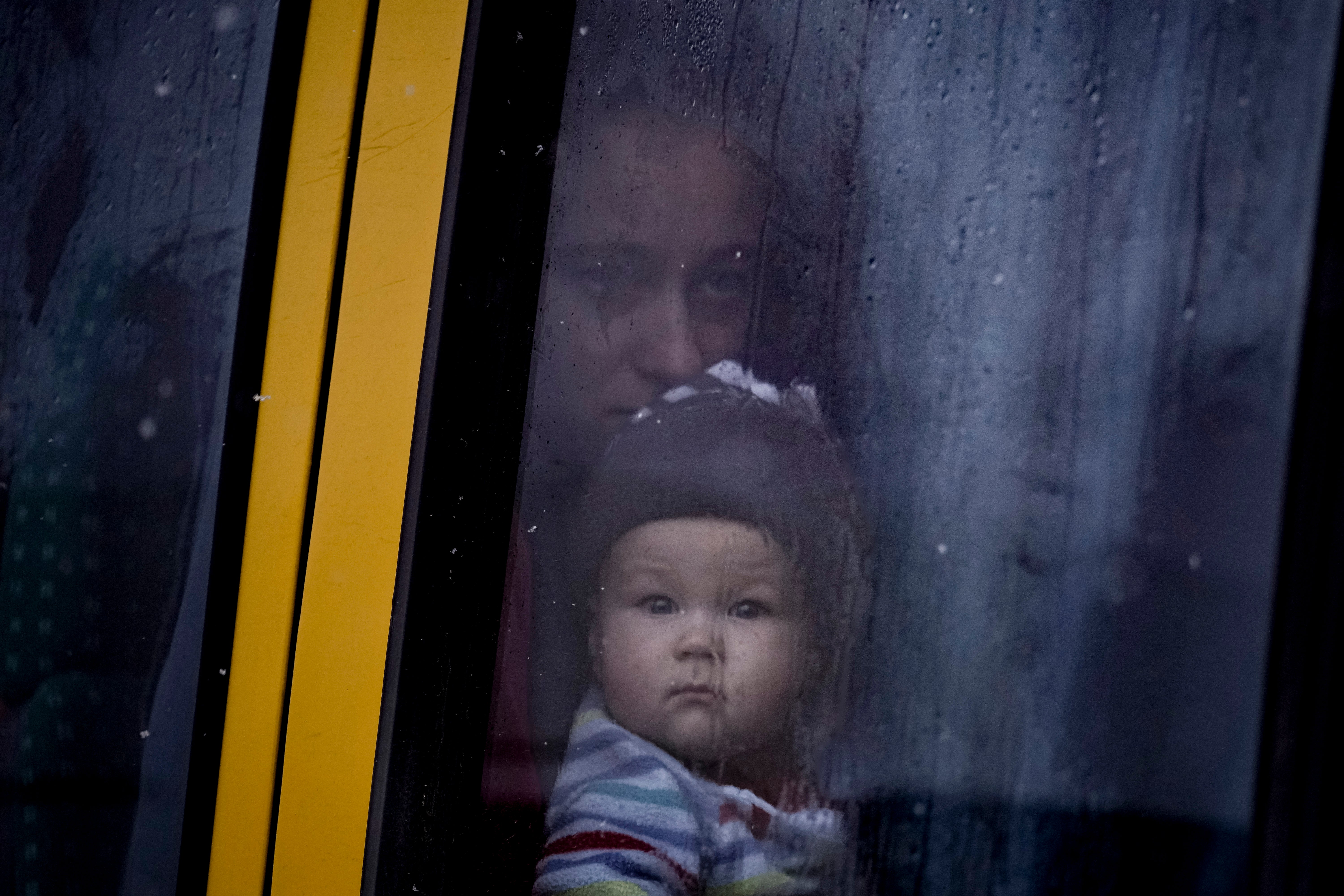 A woman and child who were evacuated from areas on the outskirts of the Ukrainian capital look out the window of a bus after arriving at a triage point in Kyiv