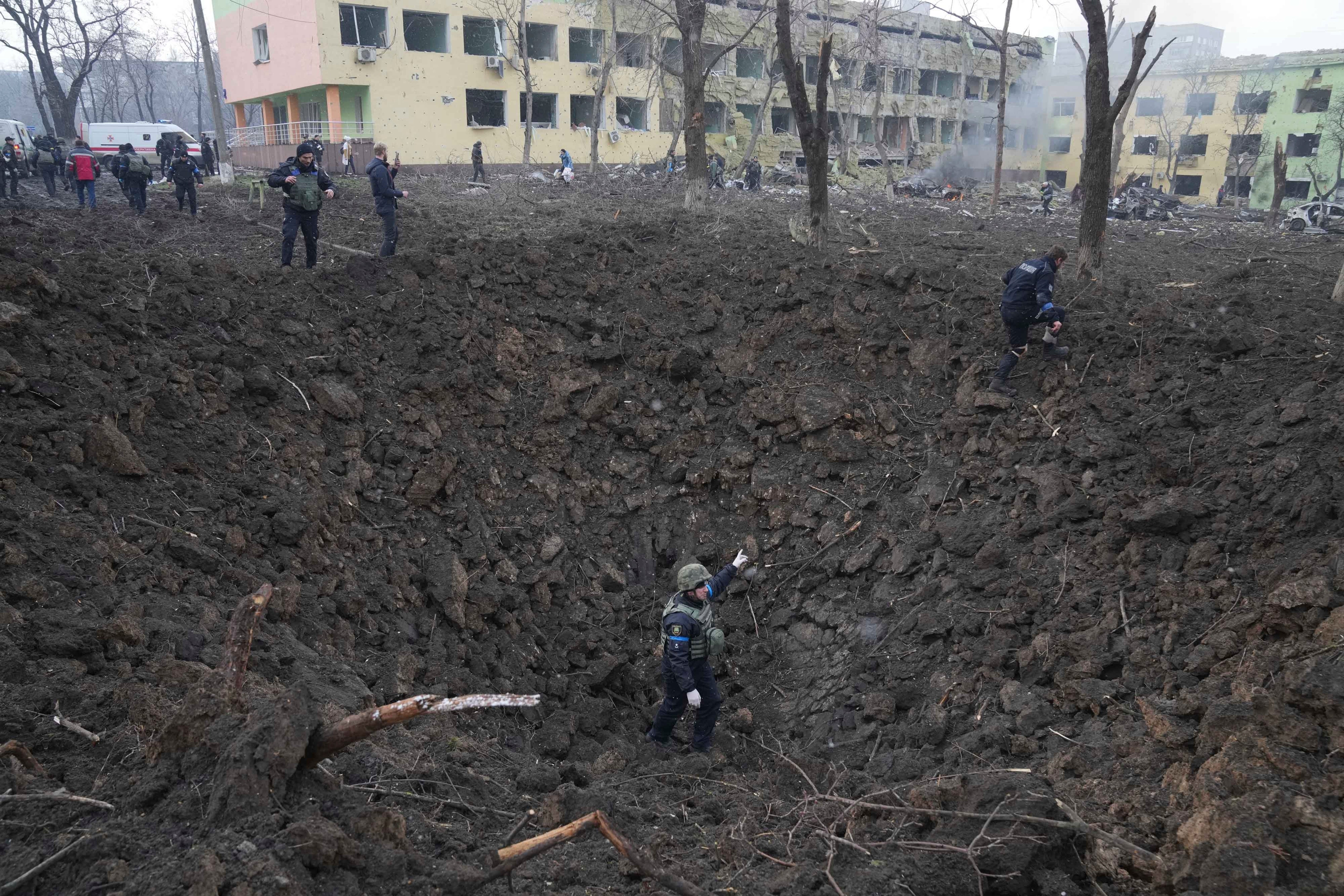 Ukrainian soldiers and emergency employees survey the damage.