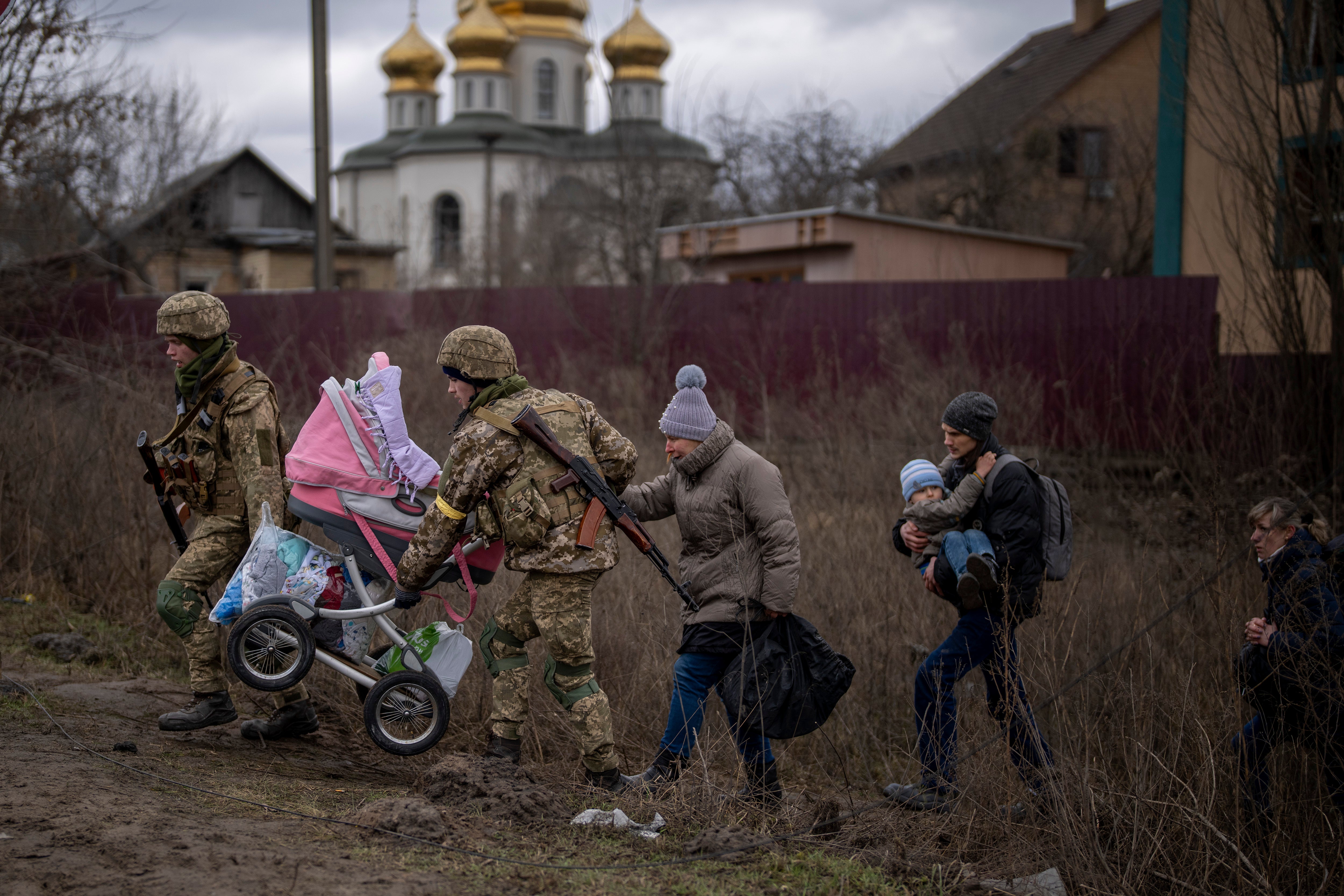 Ukrainian soldiers help a fleeing family crossing the Irpin river on the outskirts of Kyiv, Ukraine