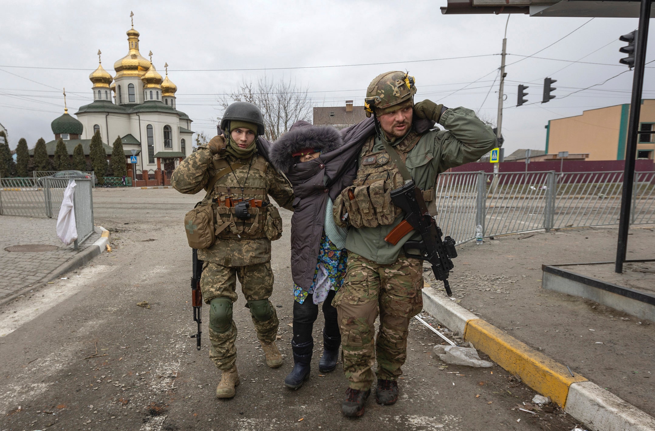 Ukrainian servicemen help an elderly woman, in the town of Irpin, Ukraine