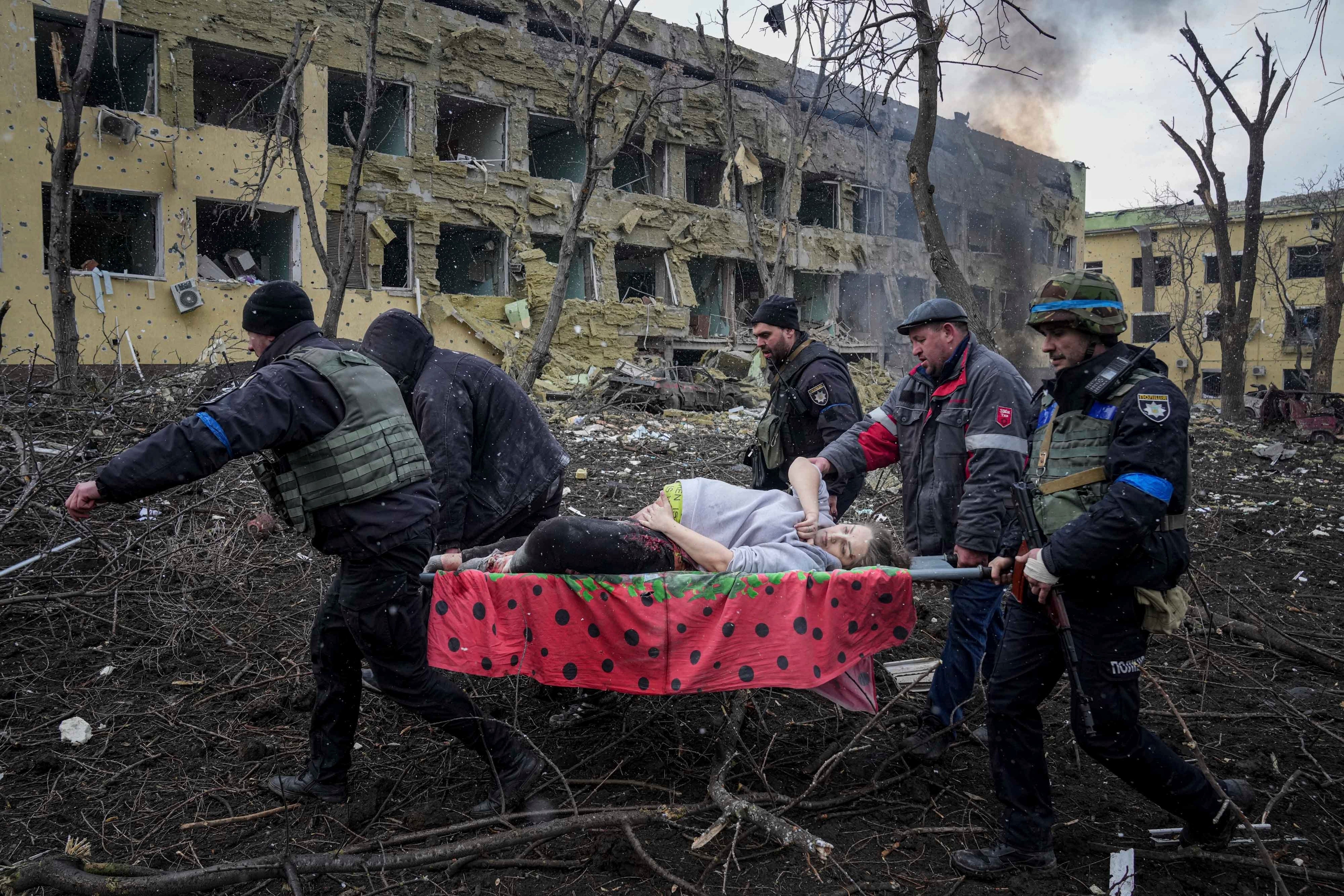 Ukrainian emergency employees and volunteers carry an injured pregnant woman from the maternity hospital, damaged by shelling, in Mariupol, Ukraine