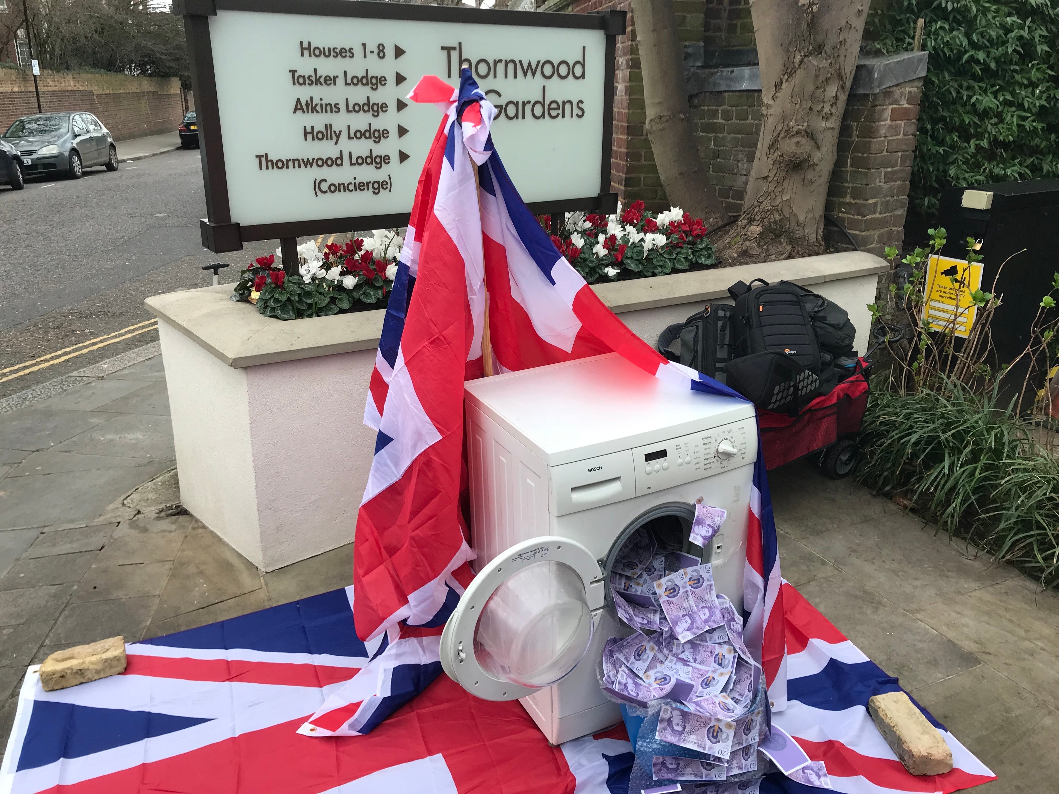 A washing machine is stuffed with fake money to protest against money laundering, in Kensington, London