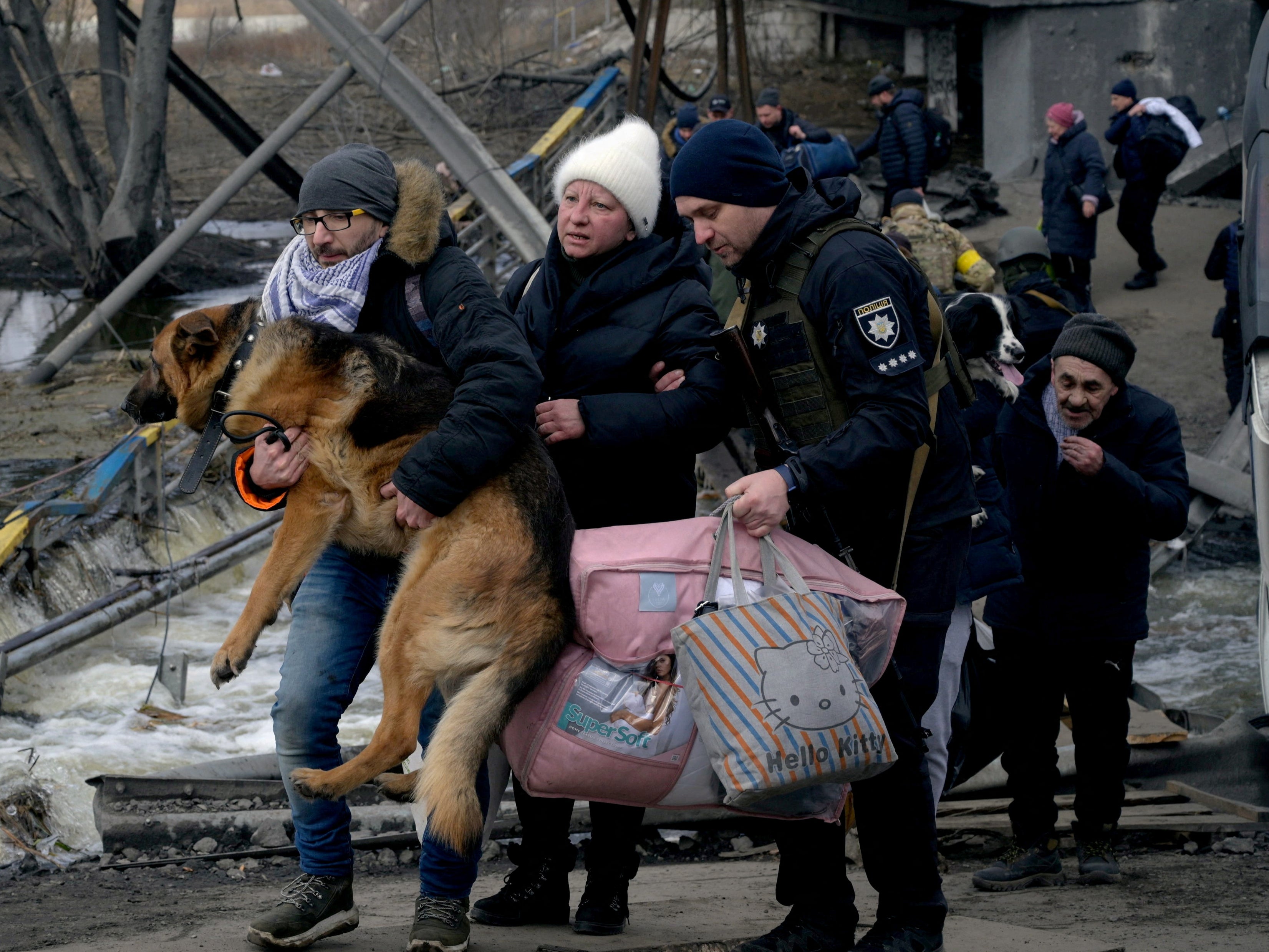 A family leaving Irpin carry their large dog