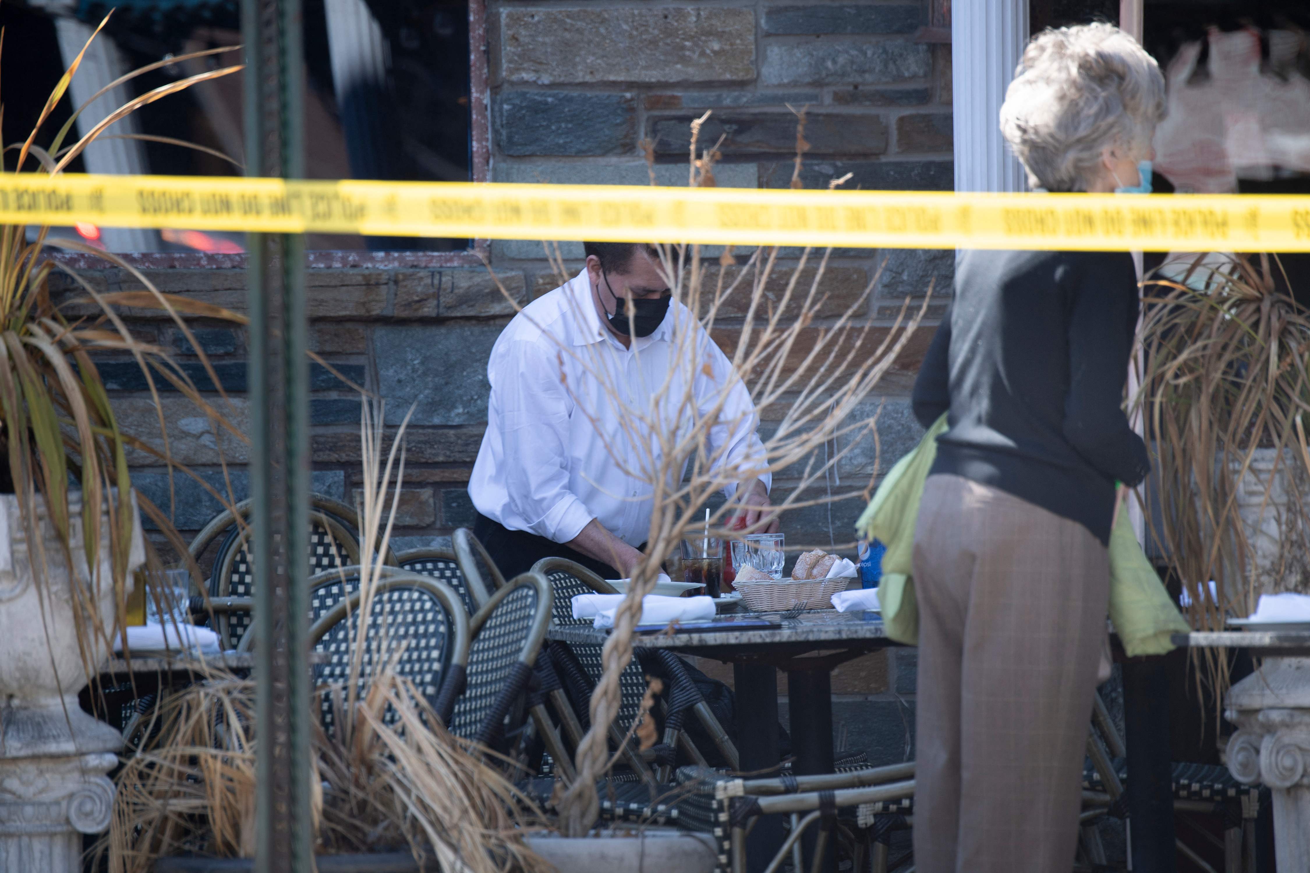 A staff member cleans a table at the scene where a vehicle crashed through an outdoor sitting area at the Parthenon Restaurant & Chevy Chase Lounge in Washington, DC, on March 11, 2022