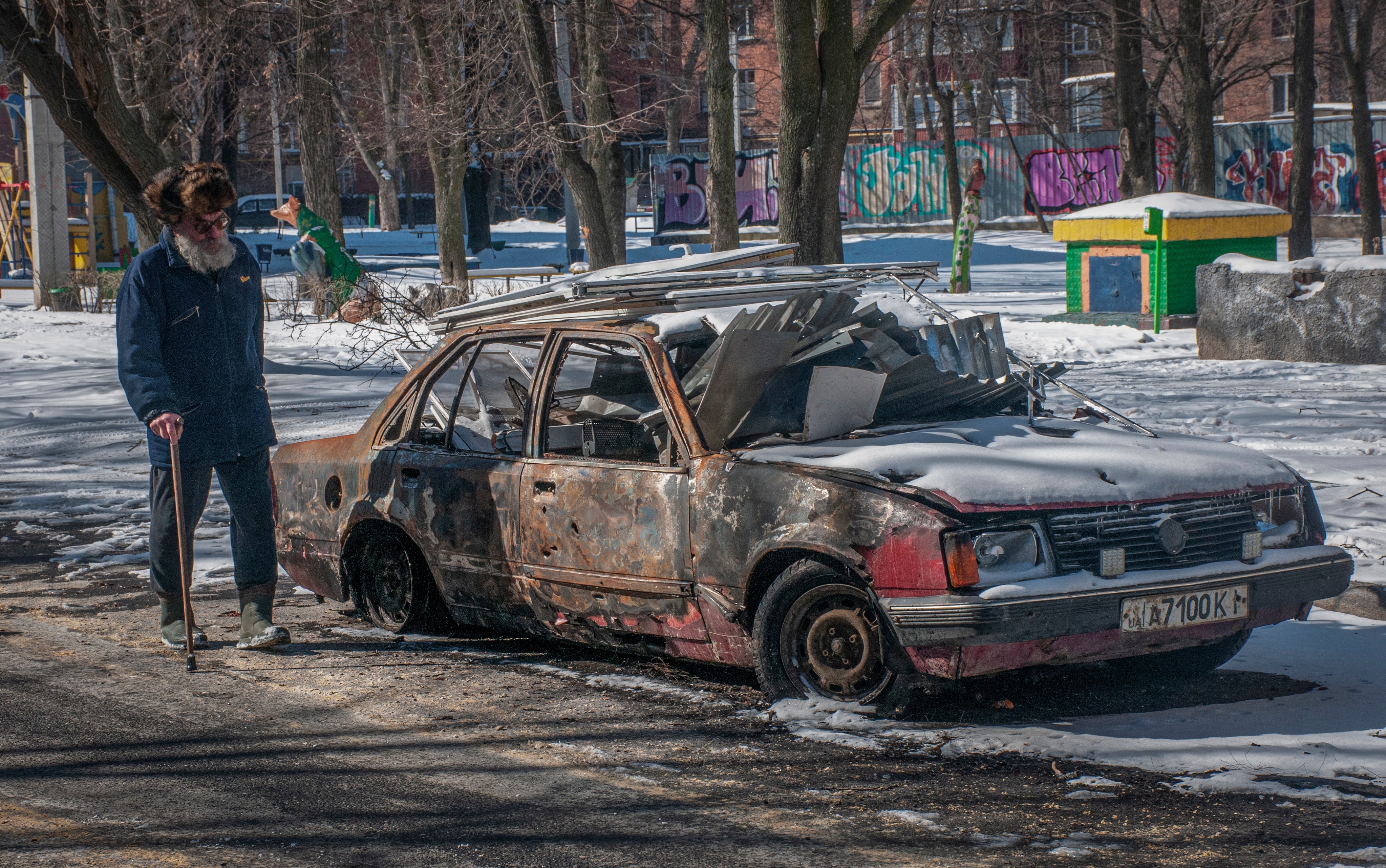 A man walks near a burned car in downtown of Kharkiv, Ukraine