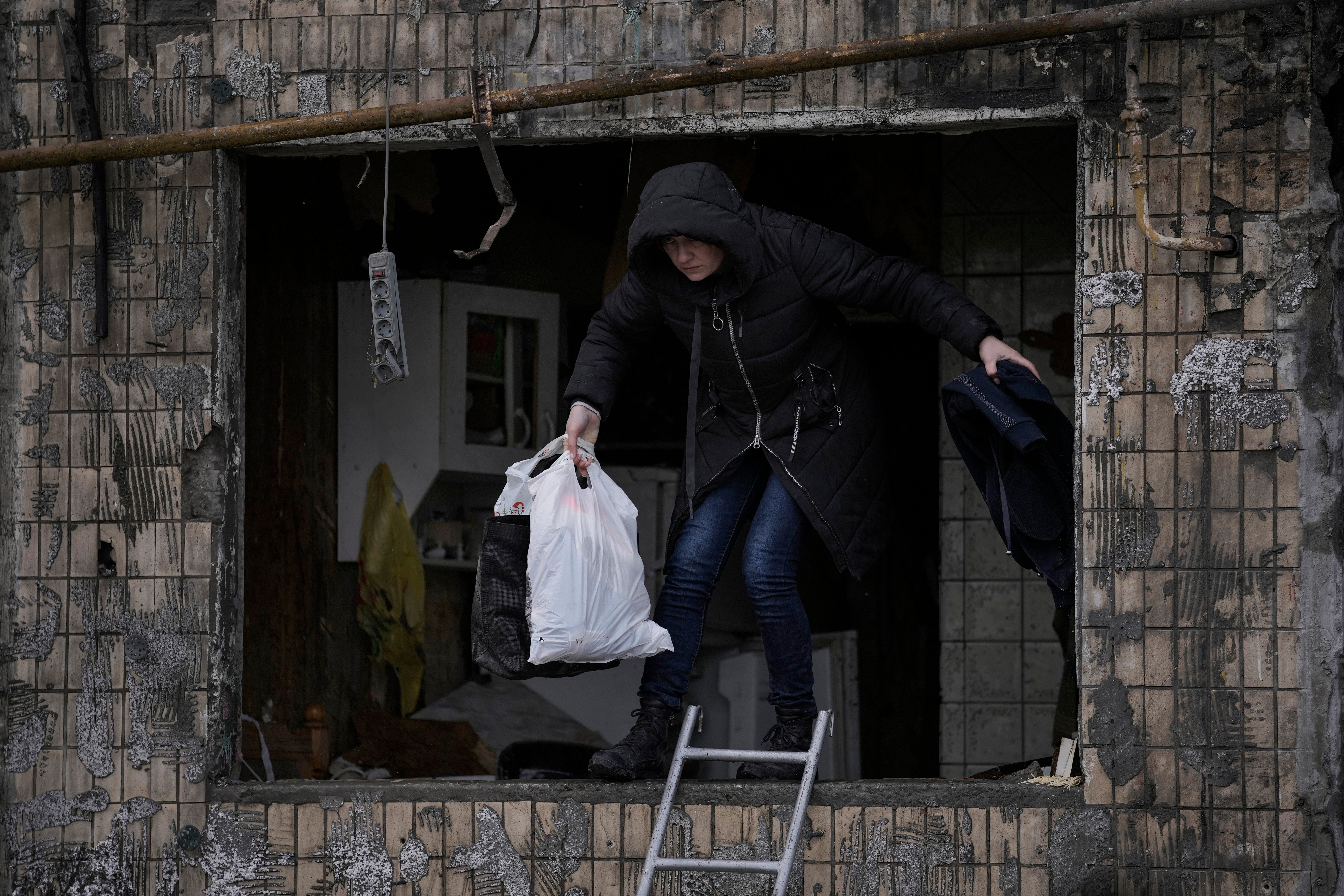 A local resident searches for her belongings in an apartment building after it was hit by artillery shelling in Kyiv