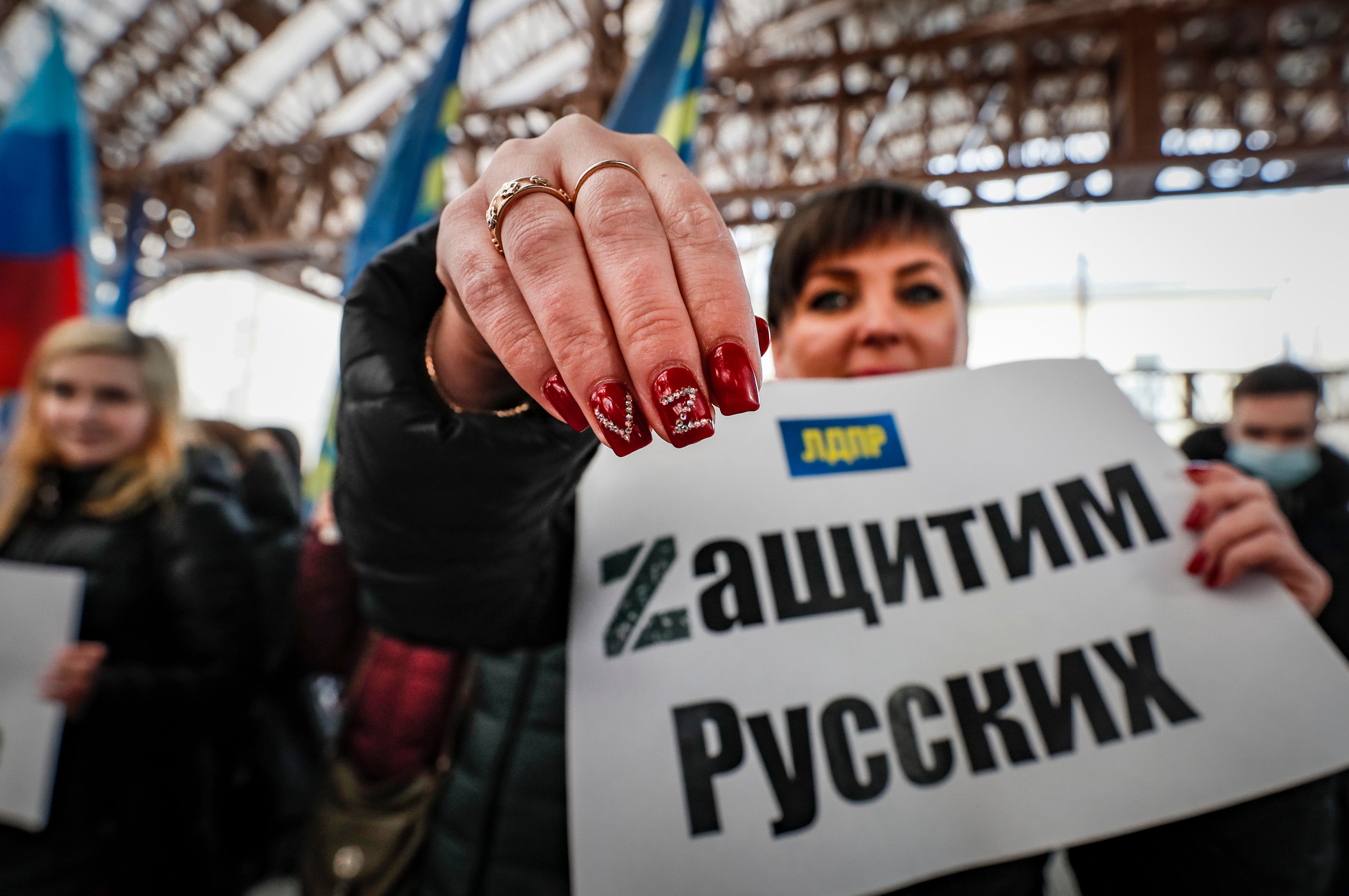 A Russian woman holds poster ‘Let’s protect the Russians’ and shows the letters V and Z on her nails during a demonstration supporting Russian troops in Moscow