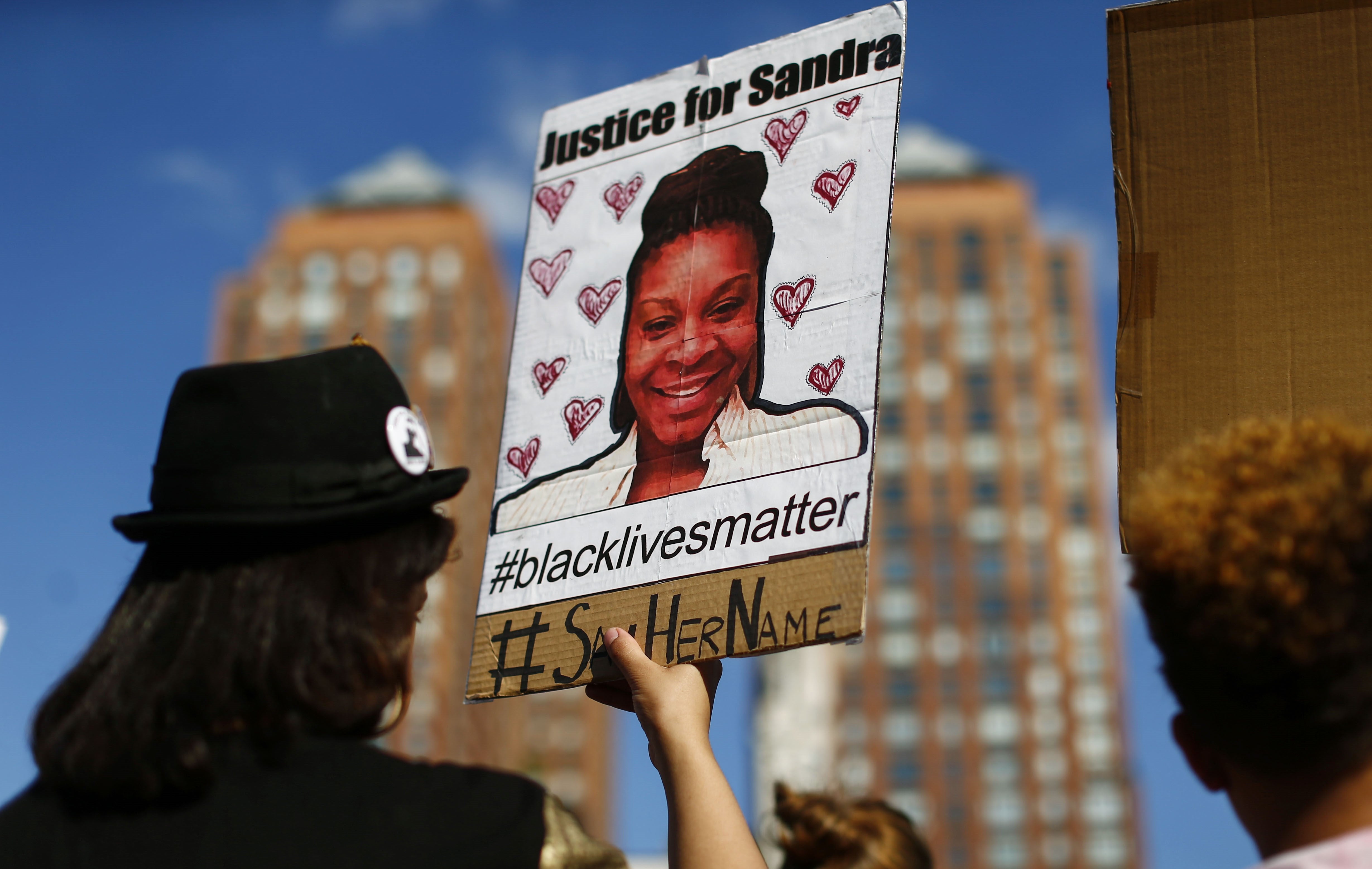 A woman holds a poster bearing the portrait of Sandra Bland, a 28-year-old woman who killed herself in a Texas jail cell