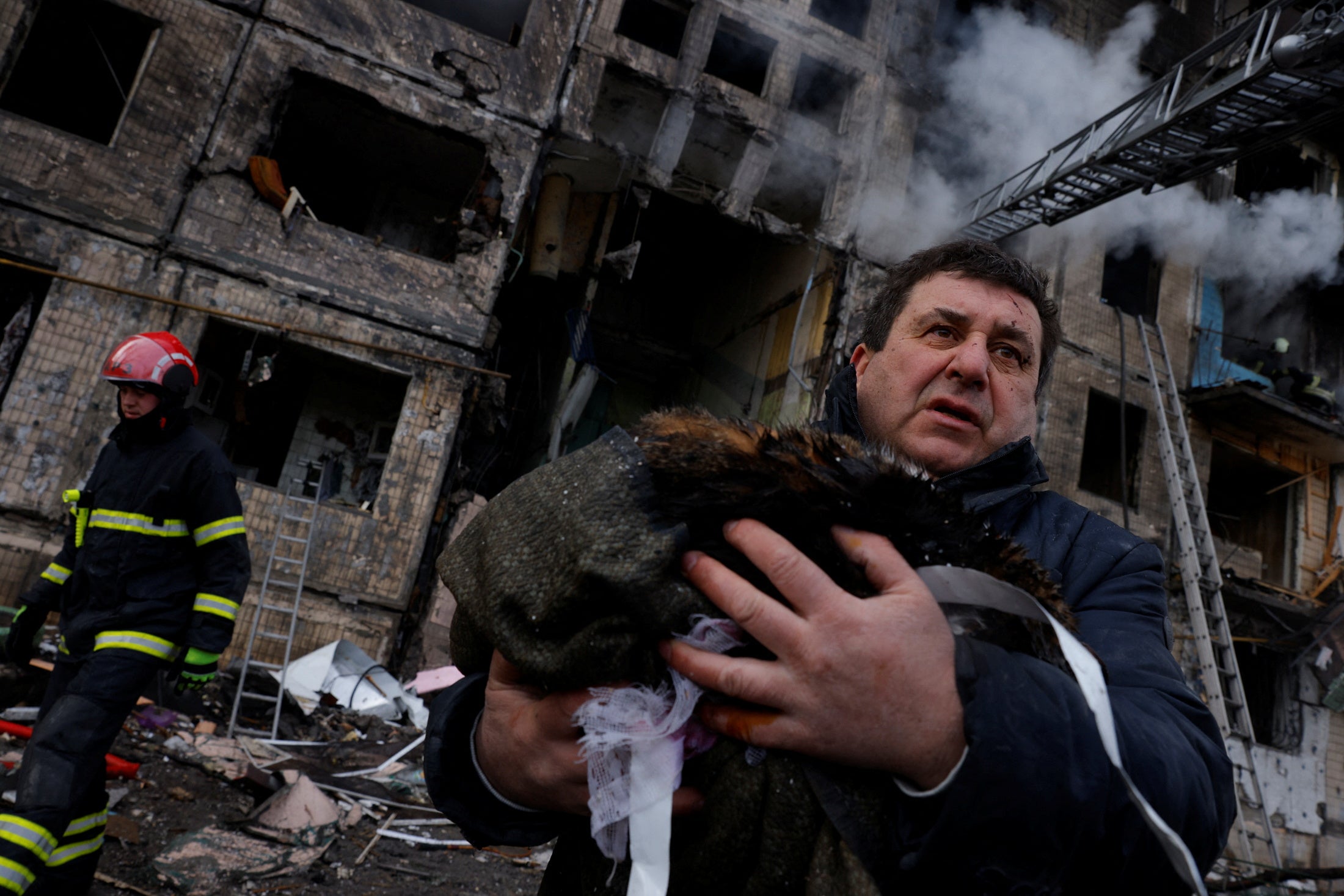 A resident carries his cat that was rescued from his home after being hit by an air strike in Kyiv