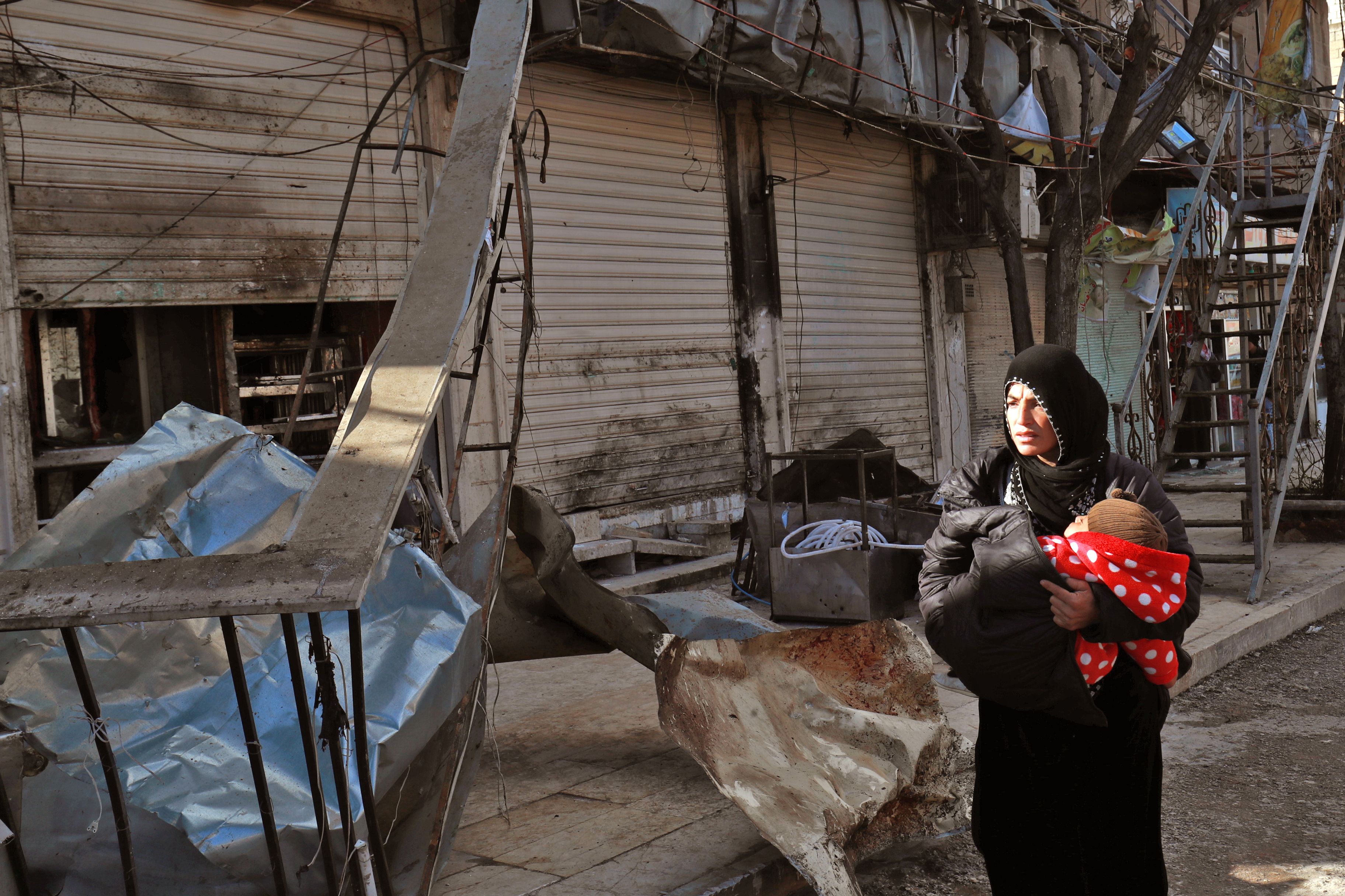 A Syrian woman walks past the site of a suicide bomb attack in the northern Syrian city of Manbij on January 17, 2019