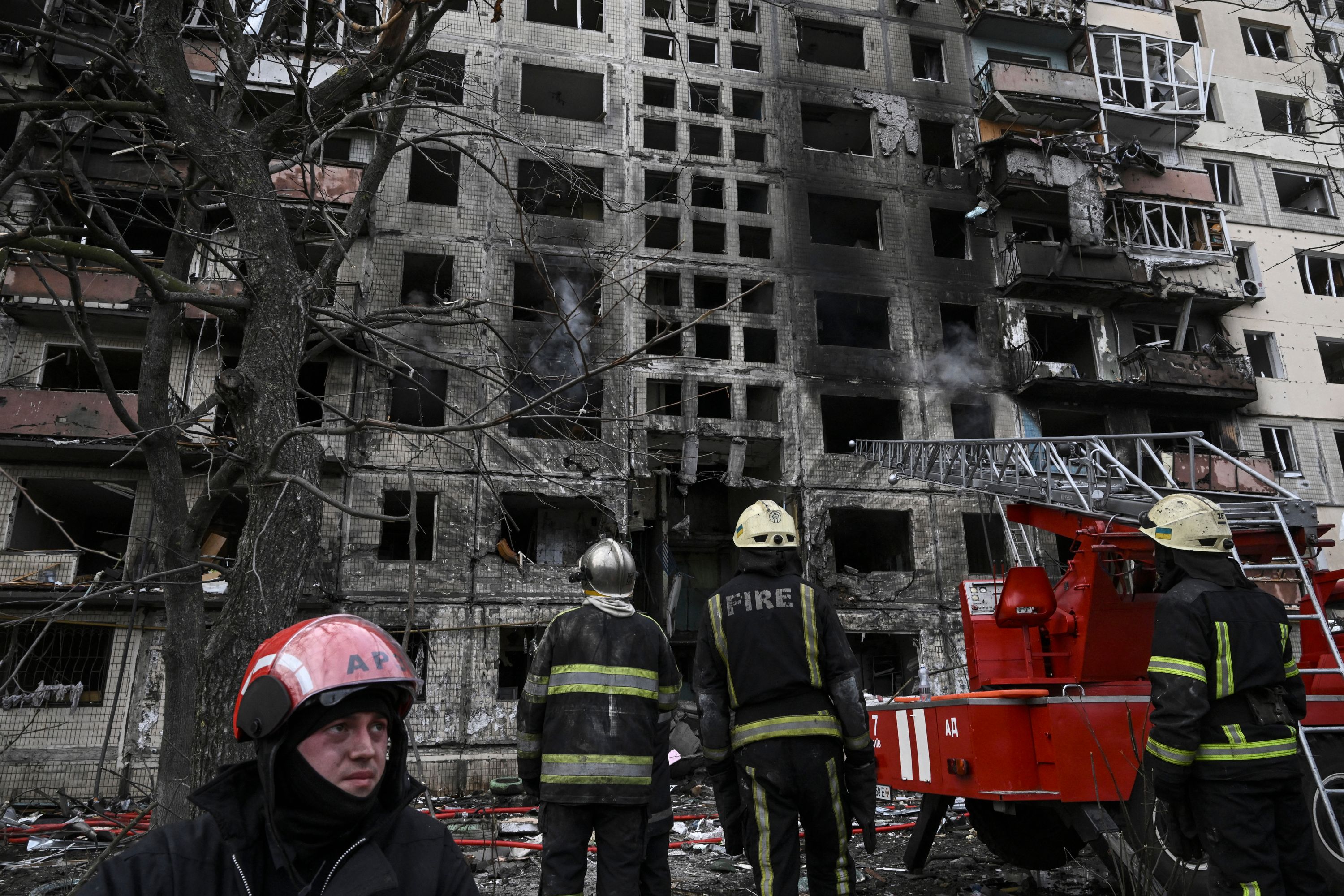 Firefighters access the situation outside an apartment building after it was shelled in Kyiv on Monday morning