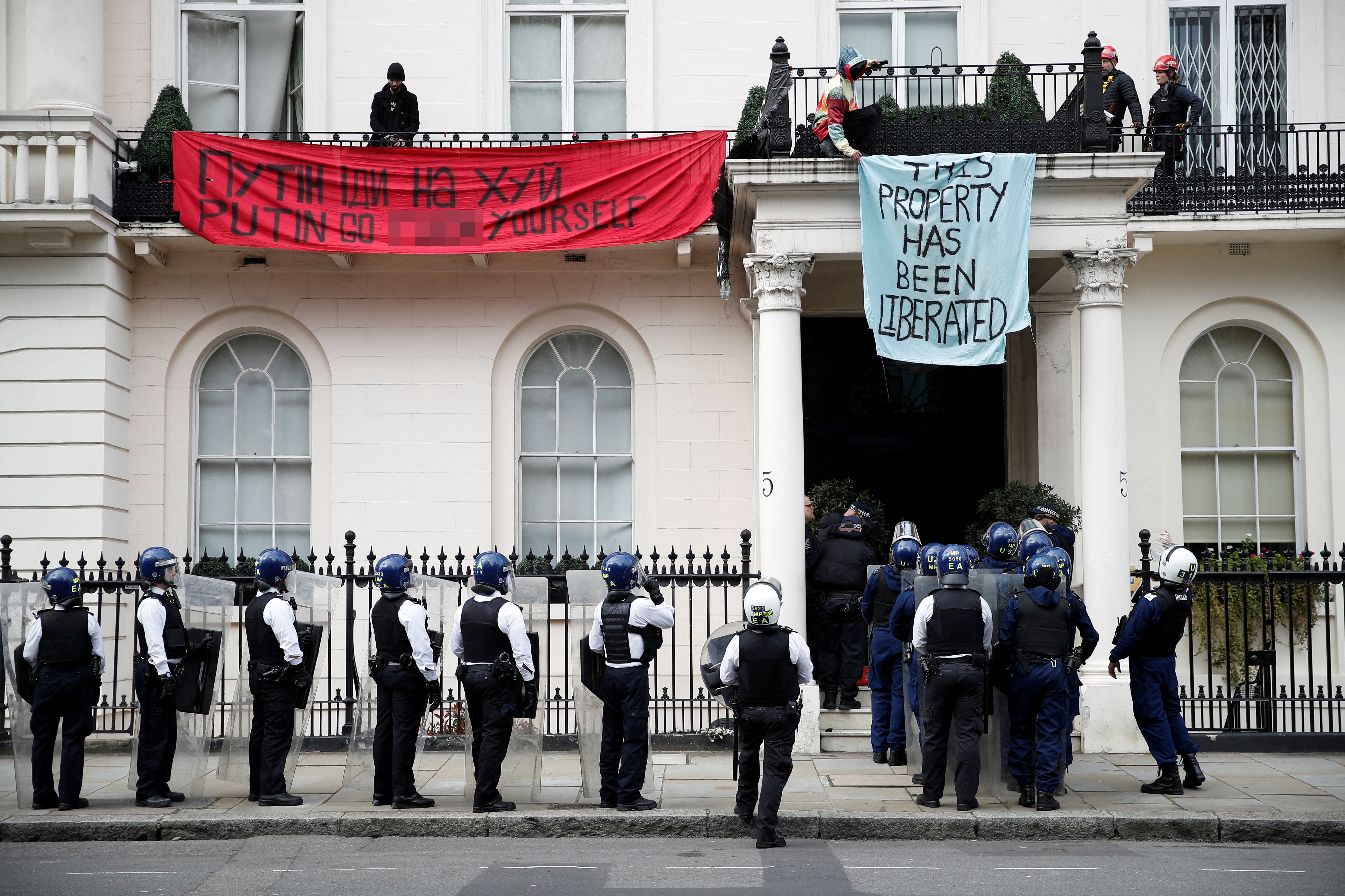 Police officers prepare to enter the mansion while squatters are inside