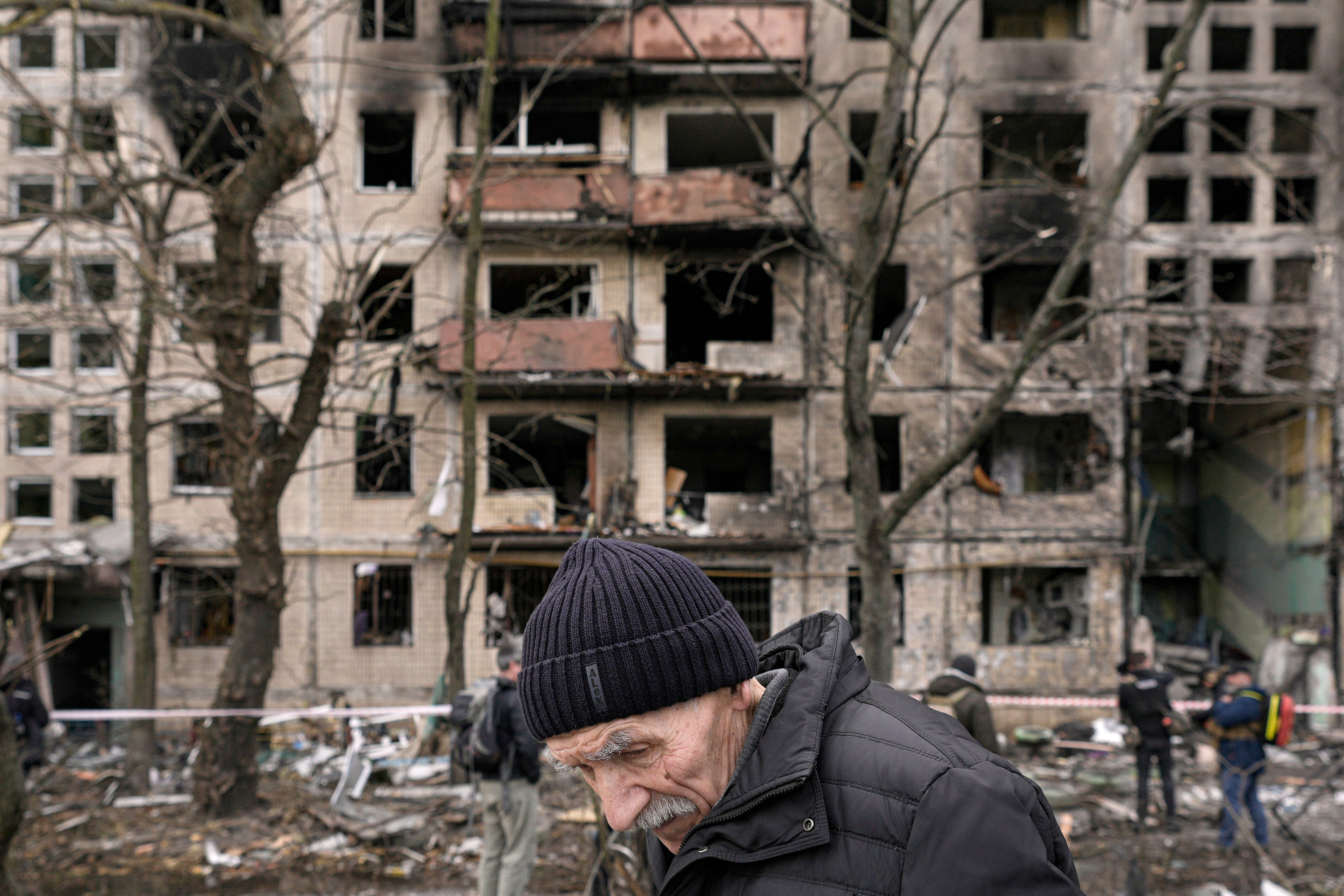 An elderly man walks outside an apartment block which was destroyed by an artillery strike in Kyiv on 14 March