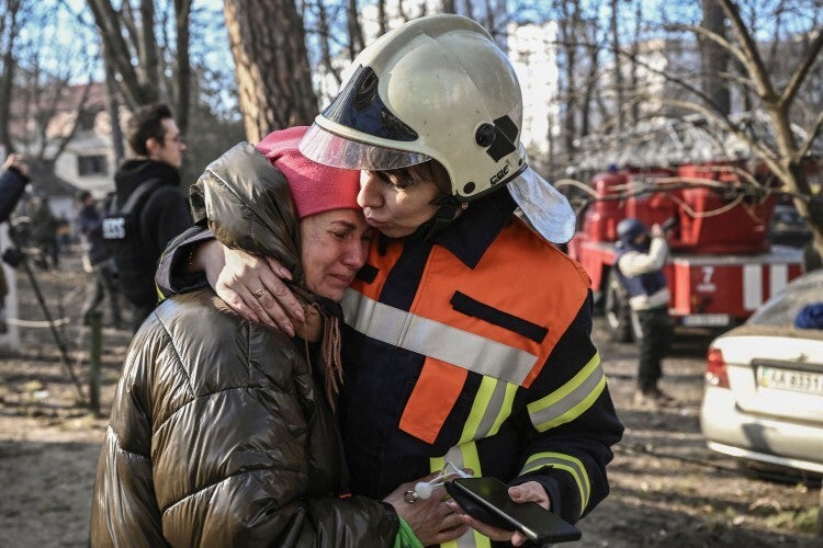 An evacuated resident being comforted outside a burning apartment building