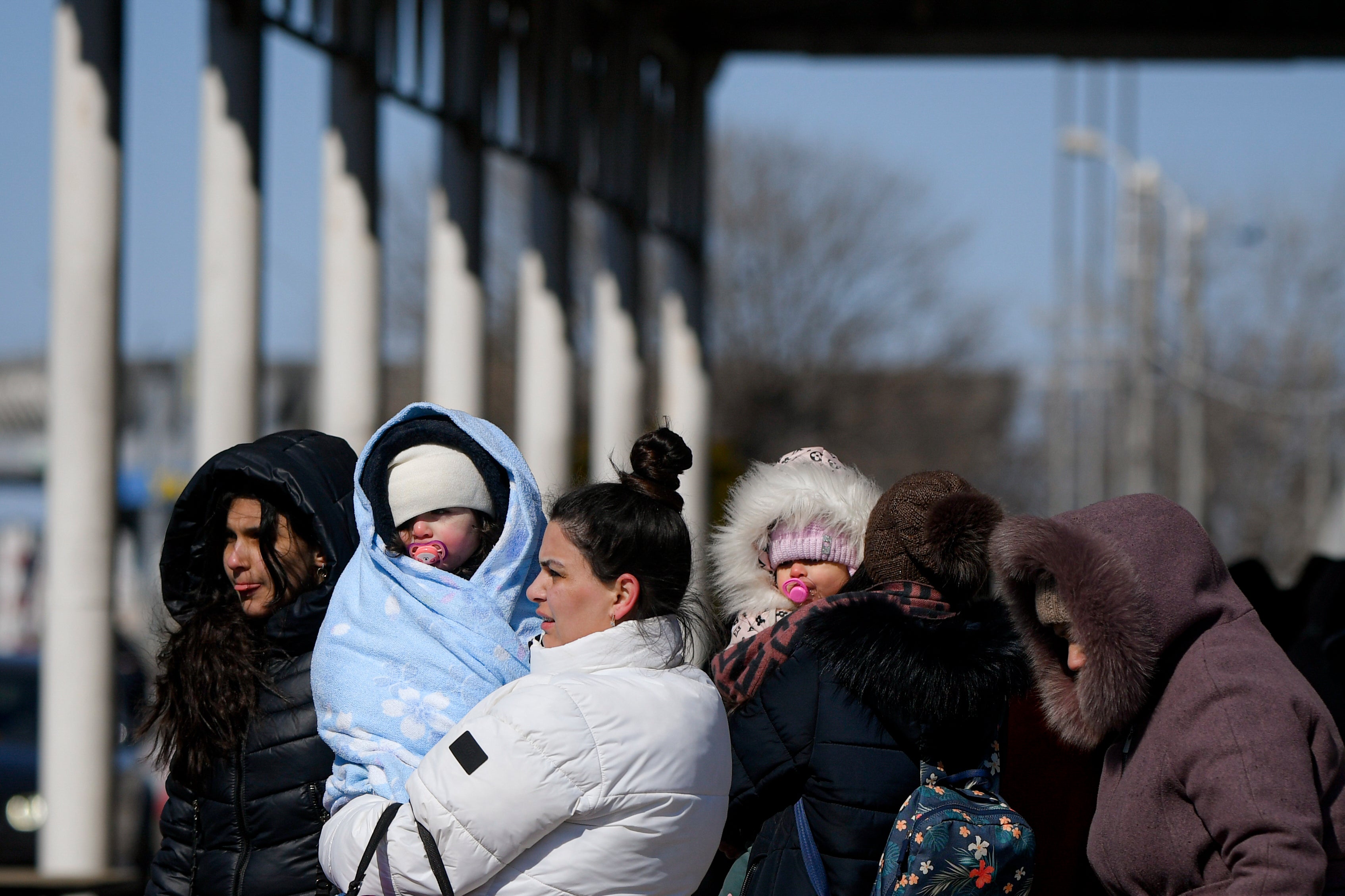 Refugees fleeing the war from Ukraine hold their babies at the Romanian-Ukrainian border (Andreea Alexandru/AP)