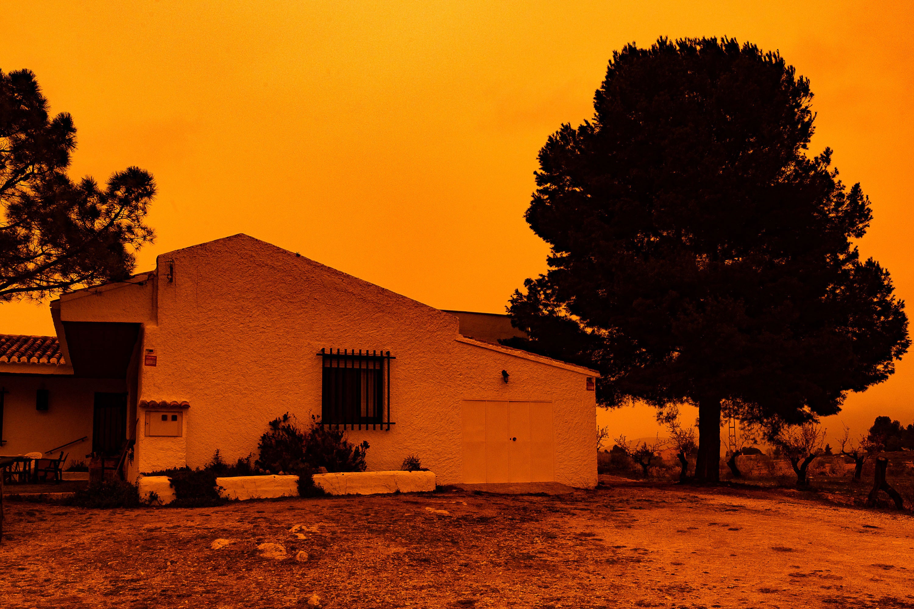 An orange sky is seen over a building in Navares, southeastern Spain on 14 March. A mass of hot air from the Sahara dumped vast amounts of dust after crossing the Mediterranean