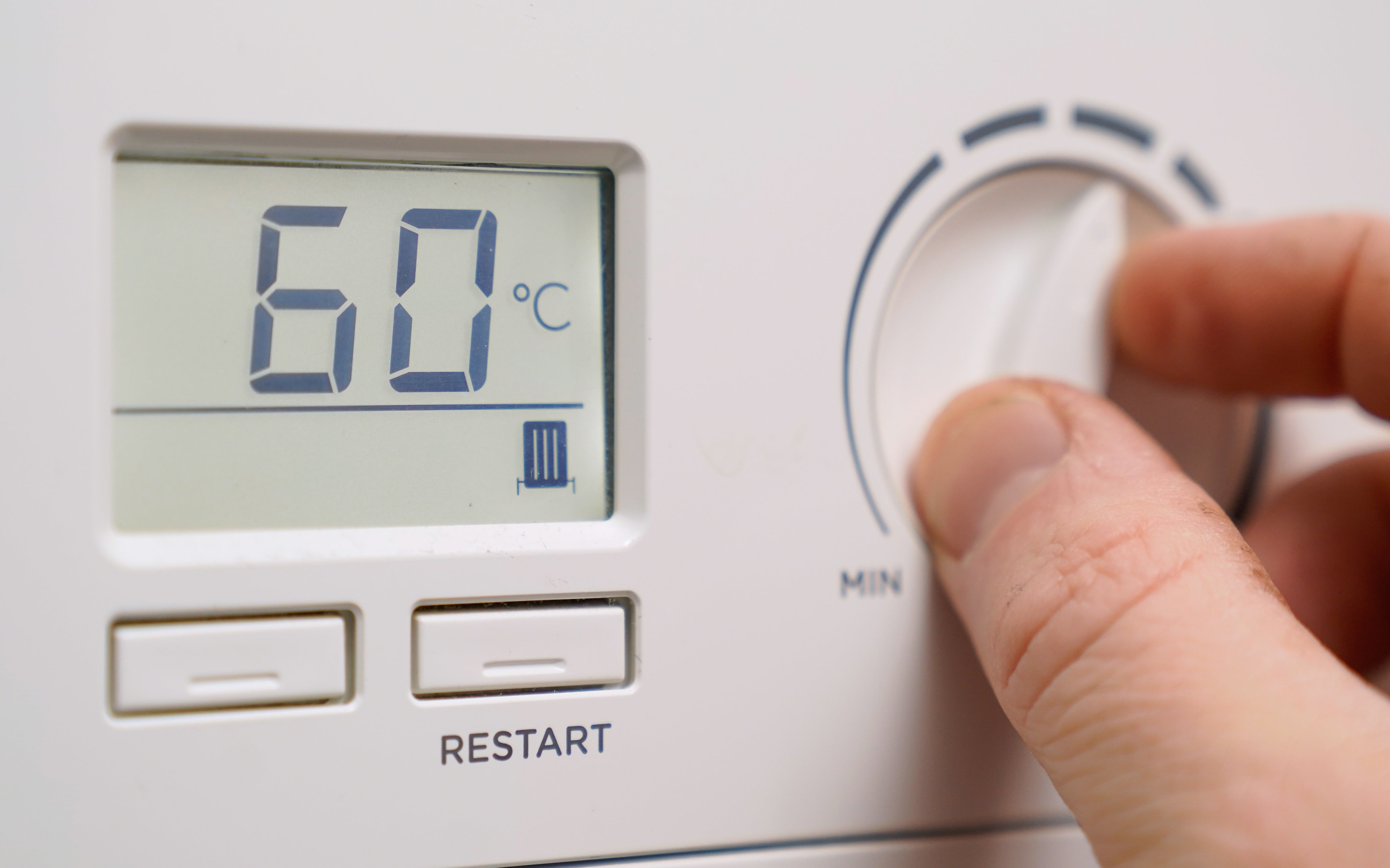 A homeowner turns down the temperature of a gas boiler (Andrew Matthews/PA)