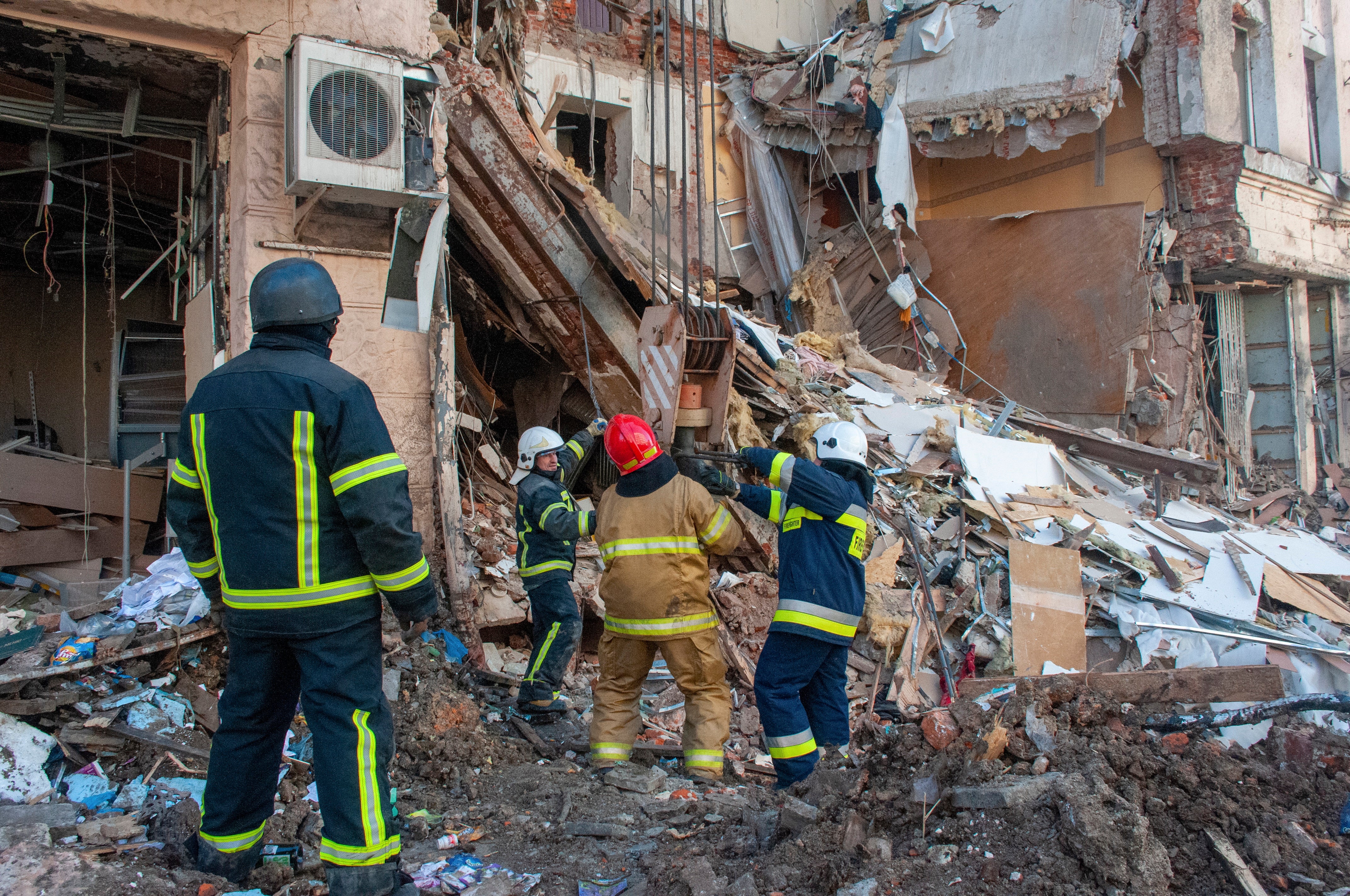 Ukrainian rescue workers remove debris from a building after a shelling in Kharkiv